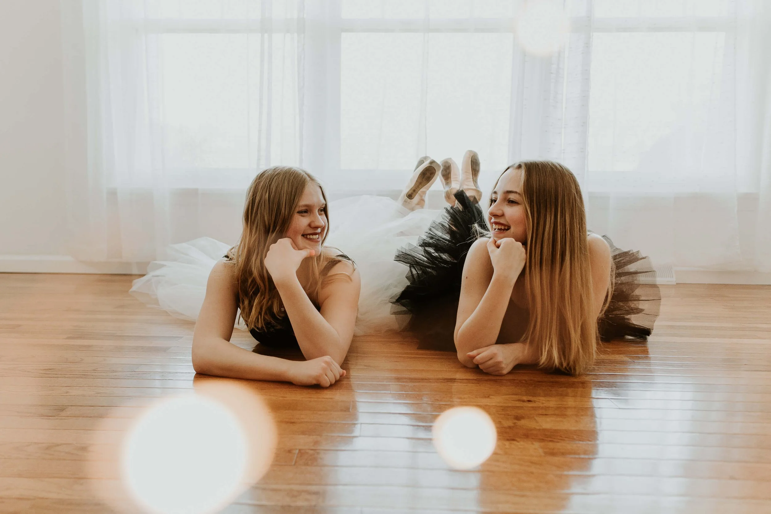 One wearing a black tutu, the other wearing white, two friends smile at each other after a ballet dance practice in Bloomington, IL