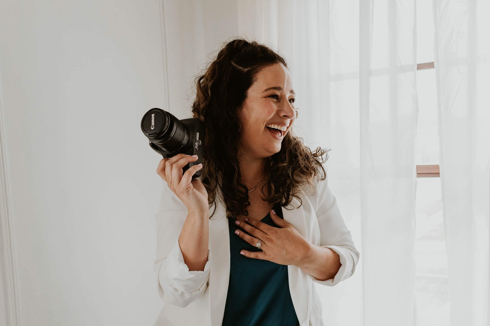 Liz Walsh holds her Canon camera while looking off to the side with a laugh on her face