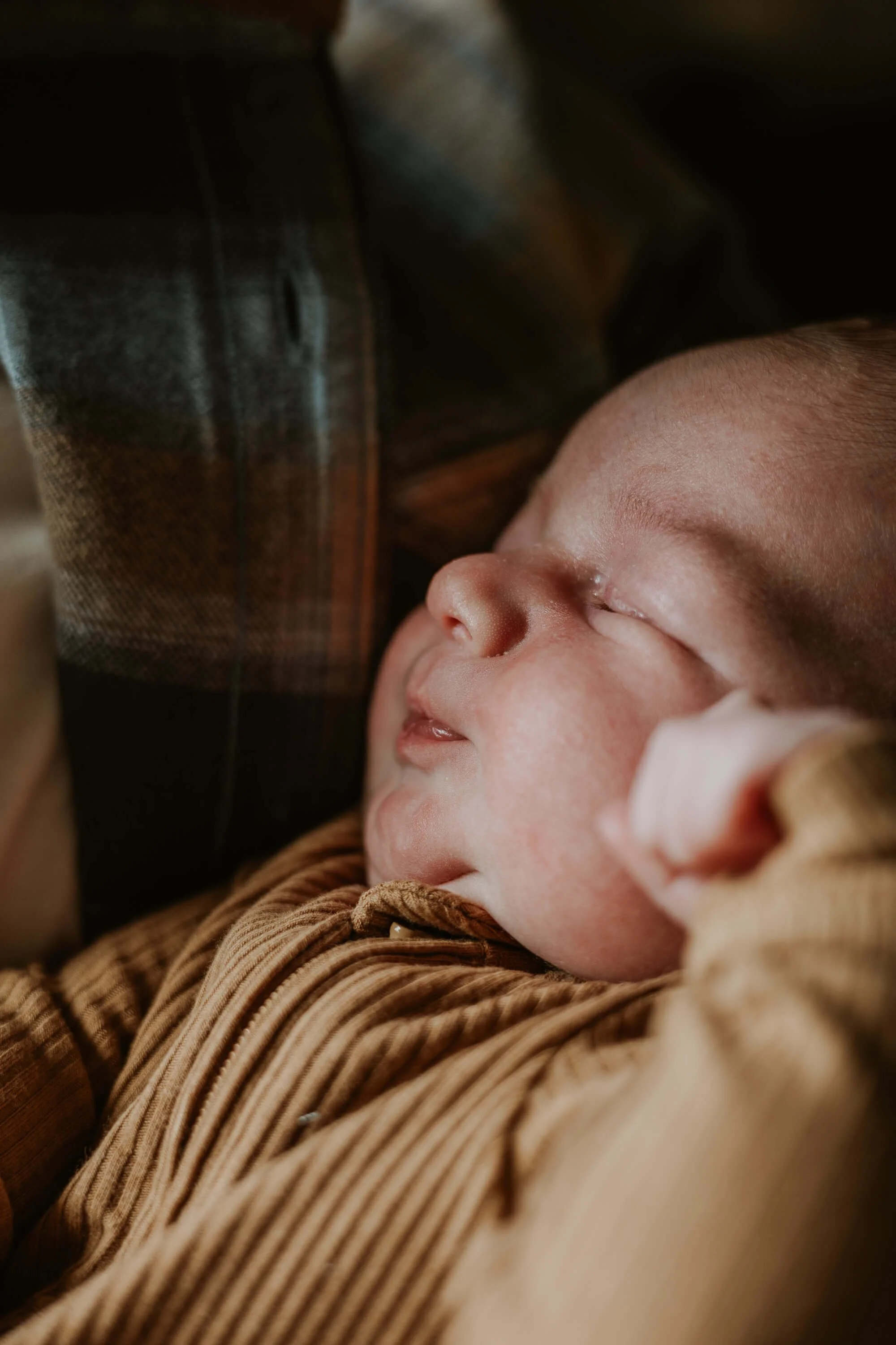 A close up of a newborn baby stretching while he sleeps
