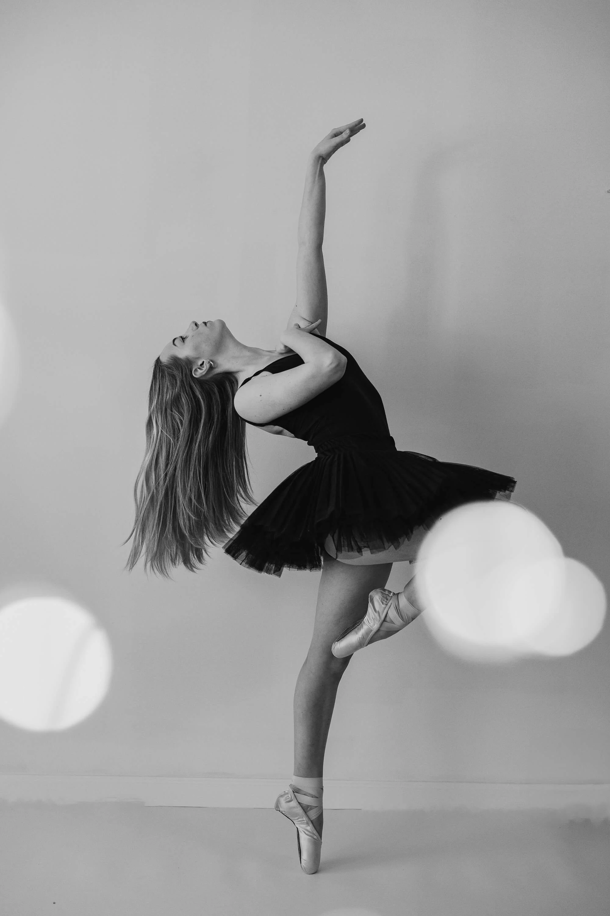 A black and white image of a dancer en pointe wearing a black tutu.