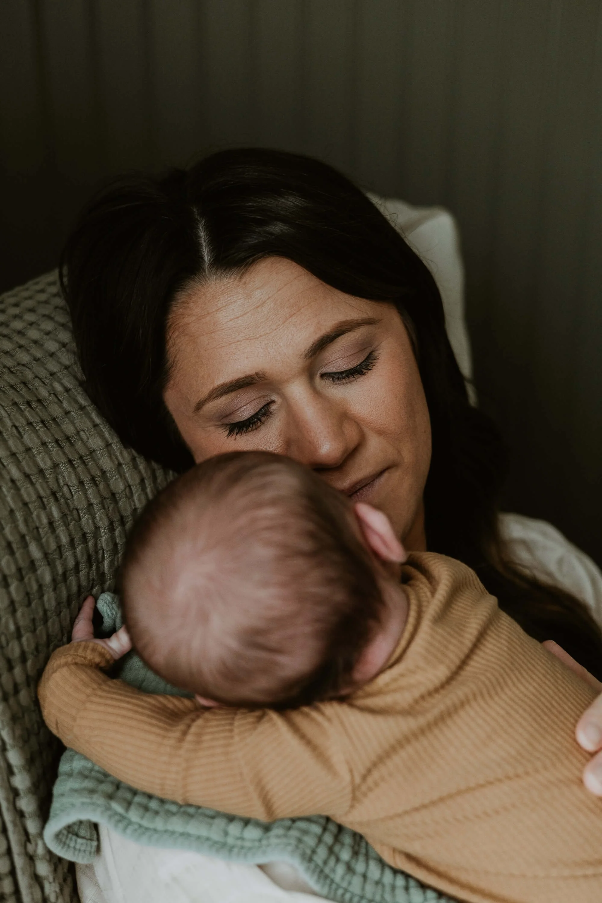 A mother snuggles her son as he's propped up on her should after a recent feeding session