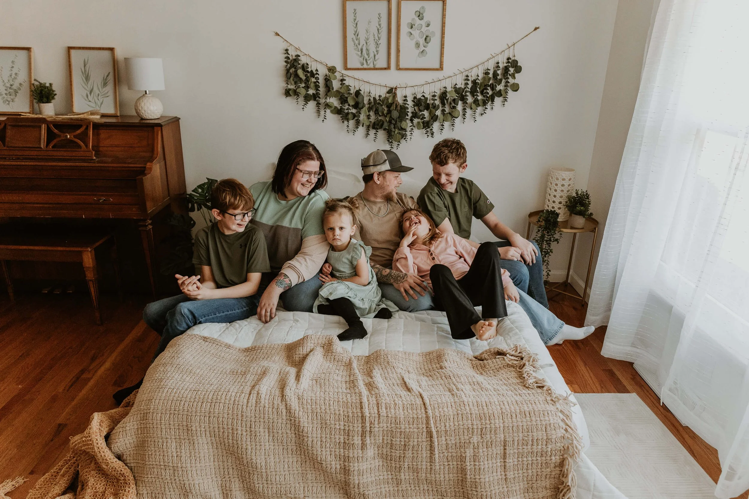 A family of six laugh while sitting cozily in bed together.