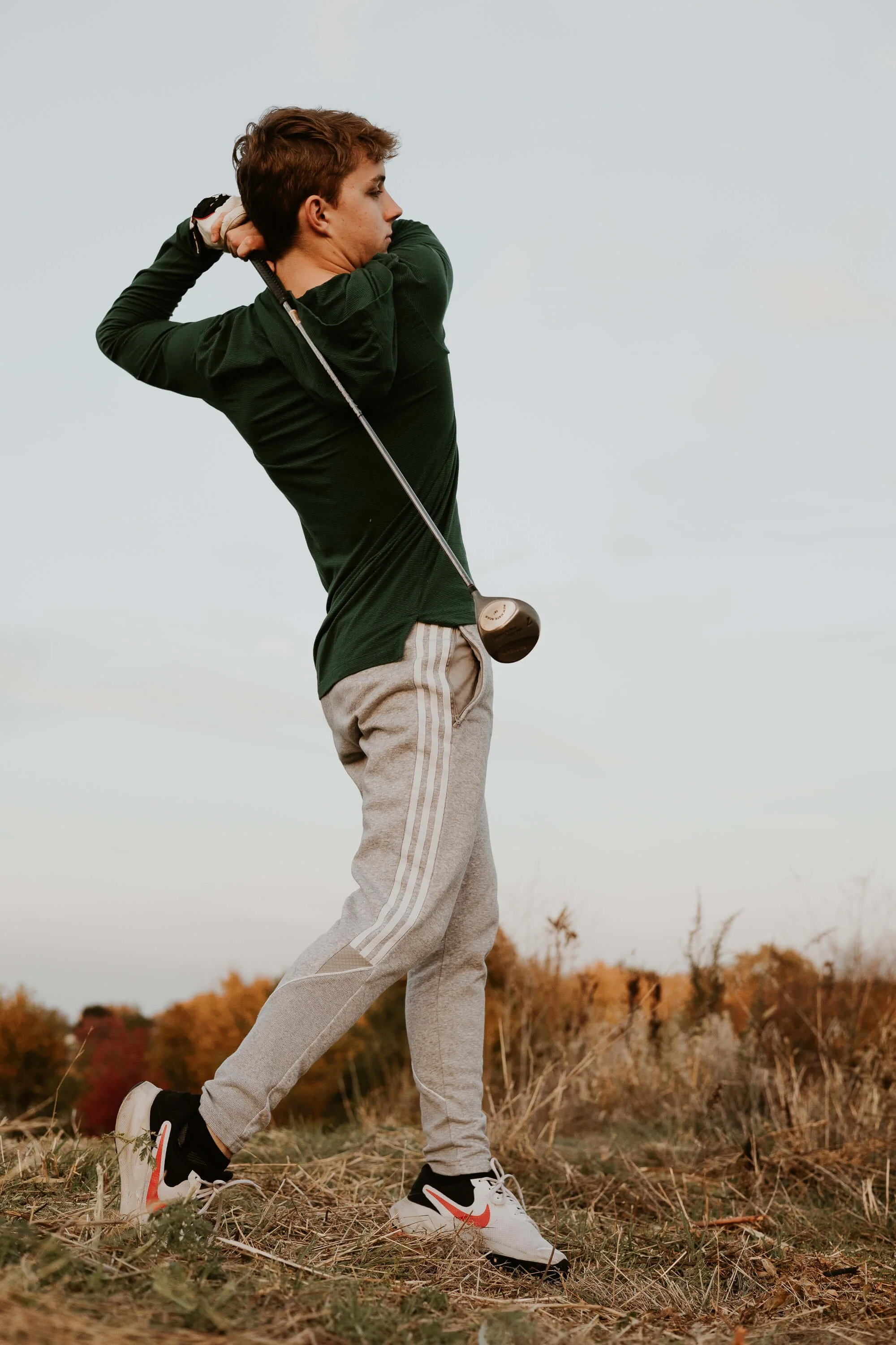 A teenager swings a golf club