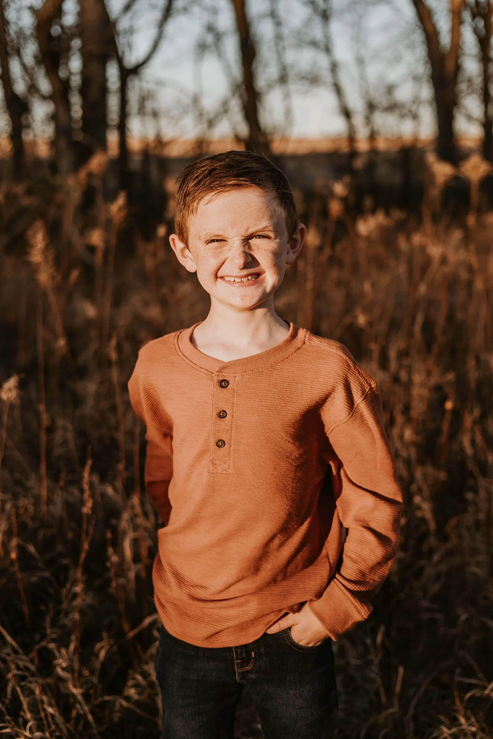 An elementary aged boy smiles proudly while posing for his family portrait