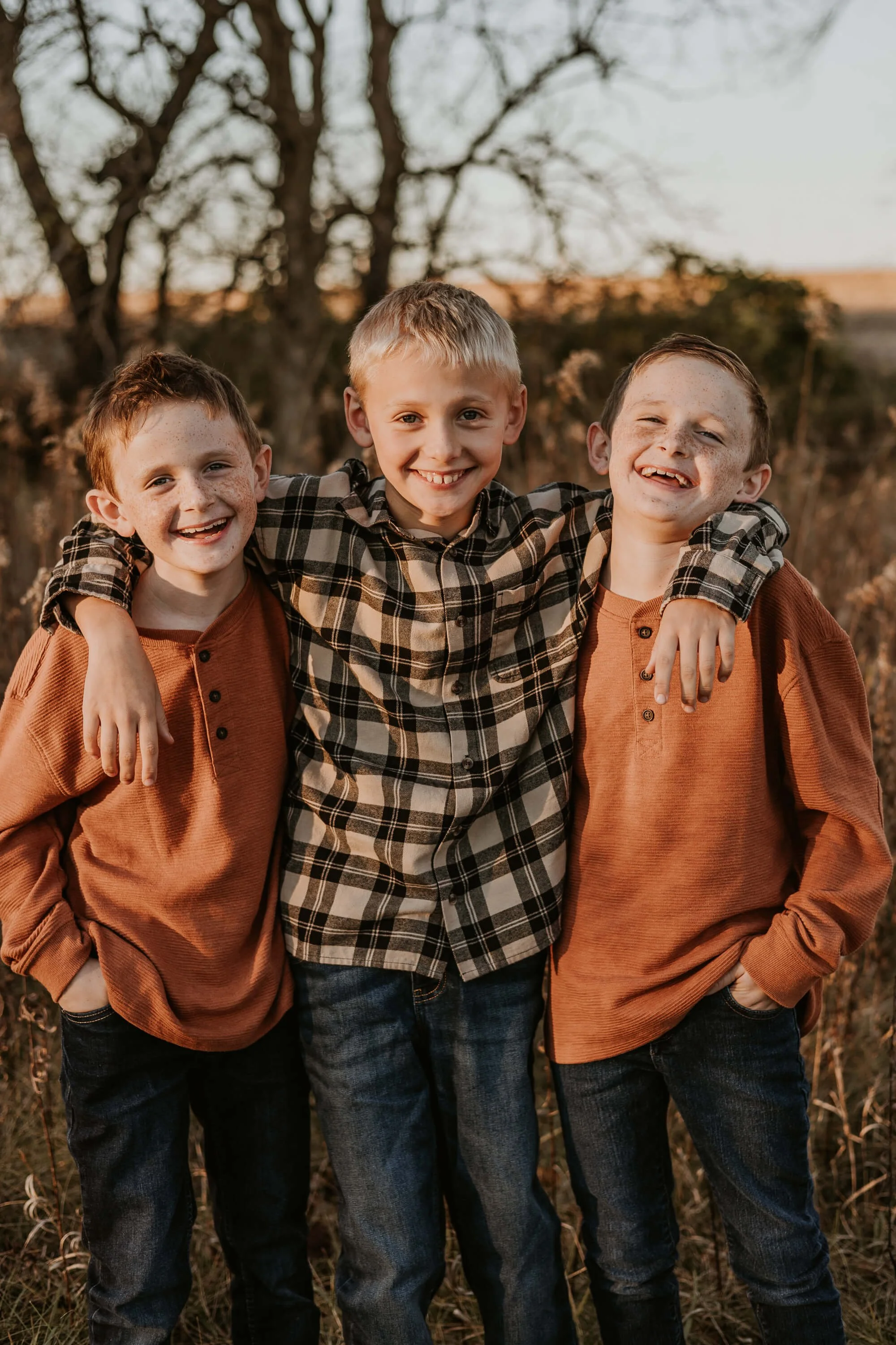 Three brothers, two of which are twins, embrace with big smiles on their faces