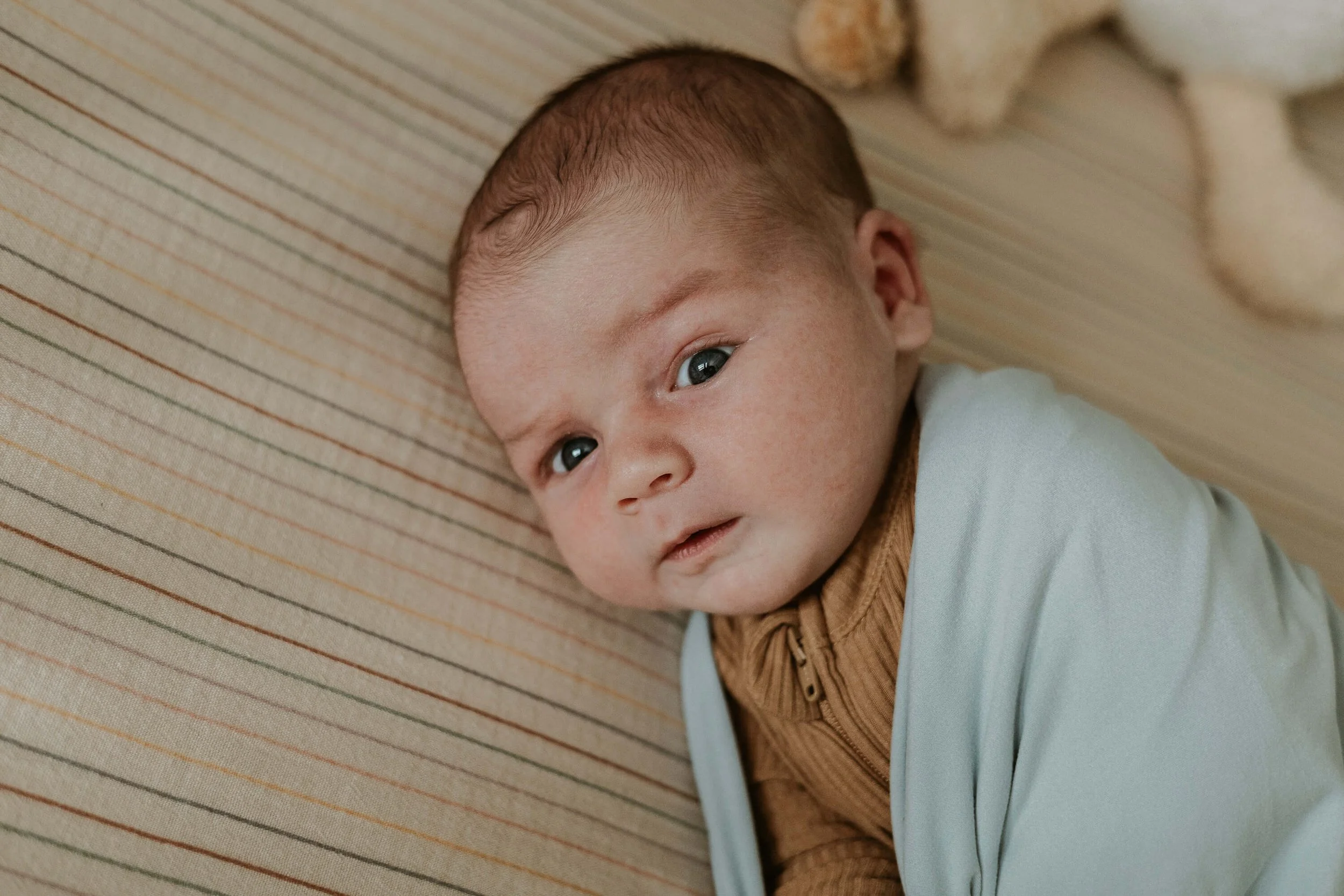A baby boy refuses to sleep in his crib and instead stares curiously out into his room