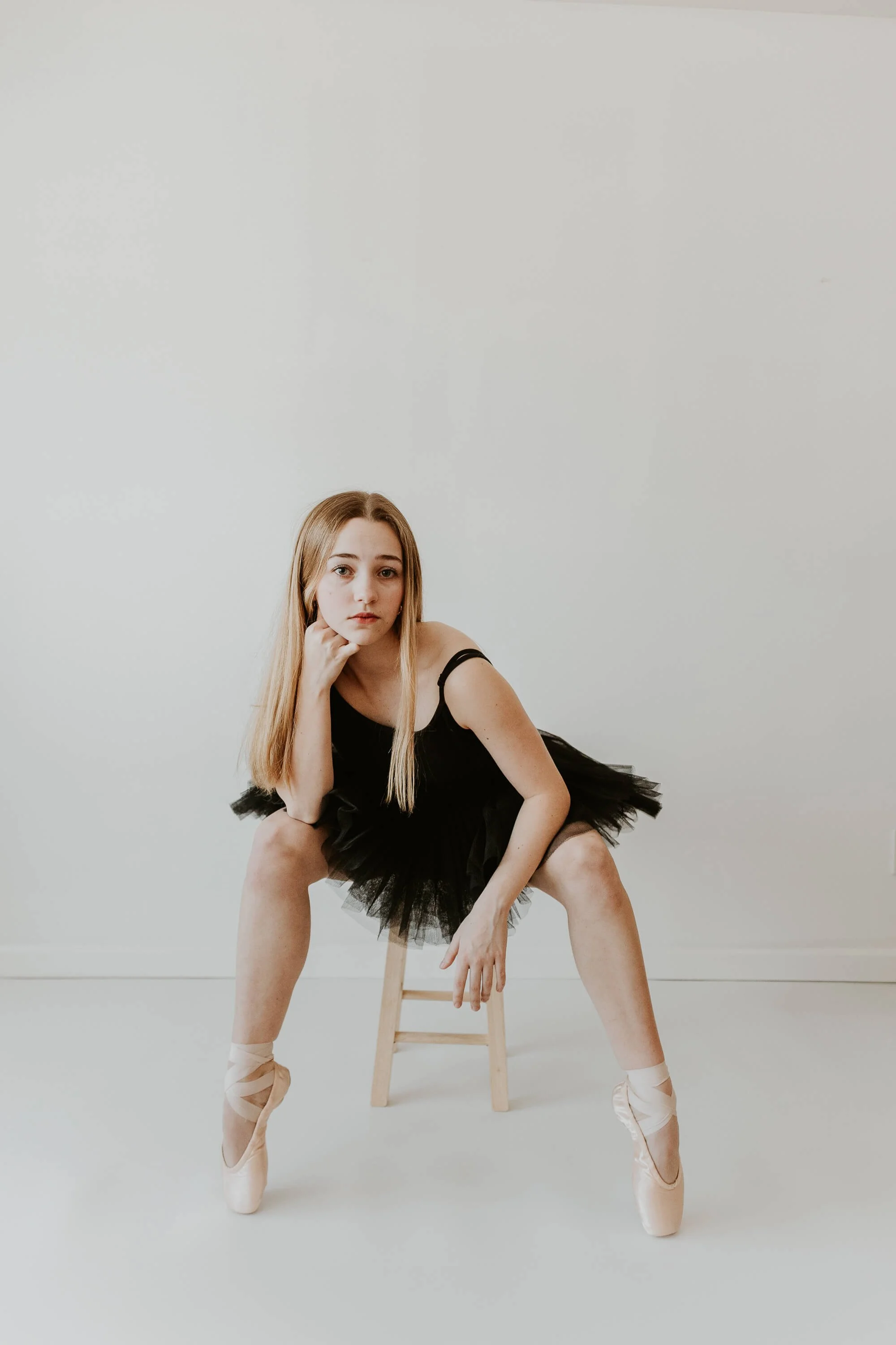A casual pose of a ballet dancer, sitting on a stool with her feet on the floor en pointe.