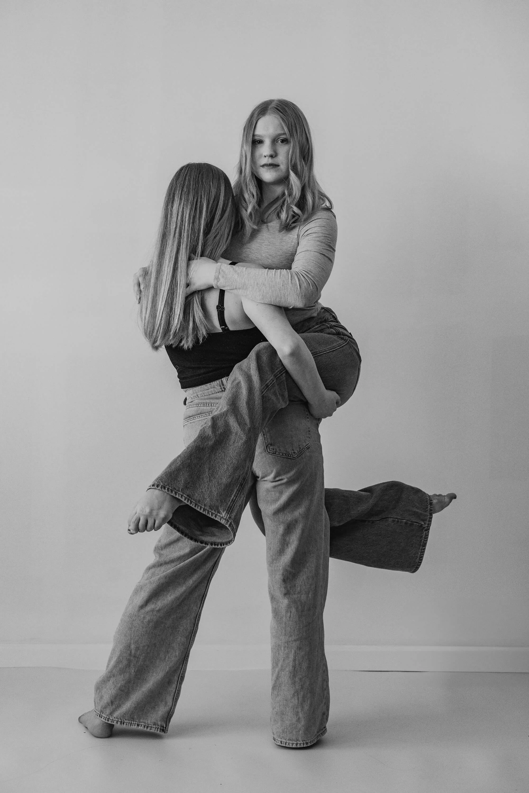 A black and white of two dancers, one holding the other on her hip.