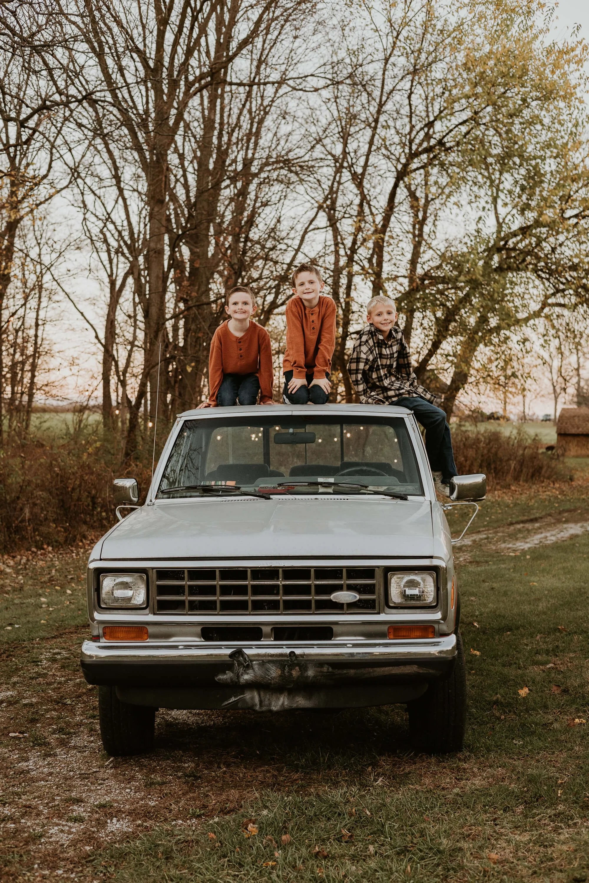Three brothers sit atop an aged pick up truck  at their family farm