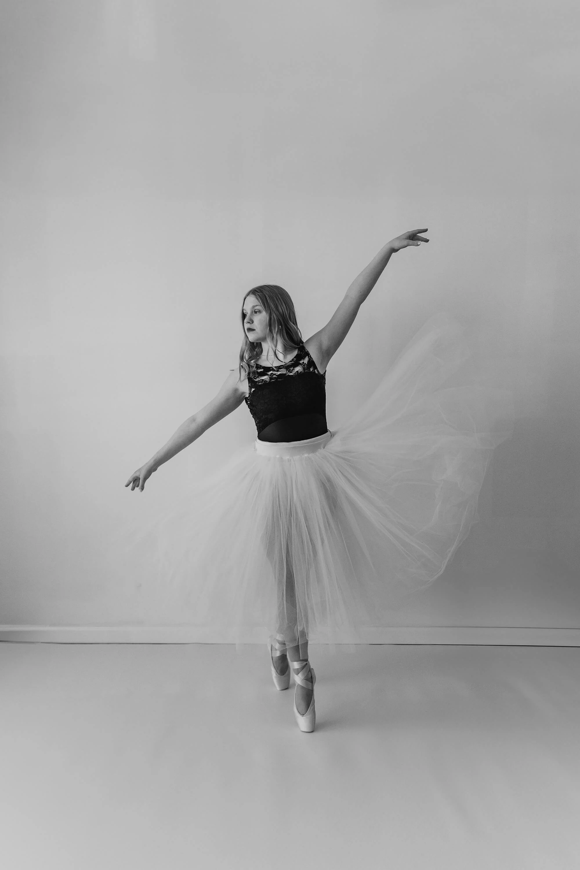 Wearing a white tutu, a talented Bloomington IL ballerina holds a pose en pointe.