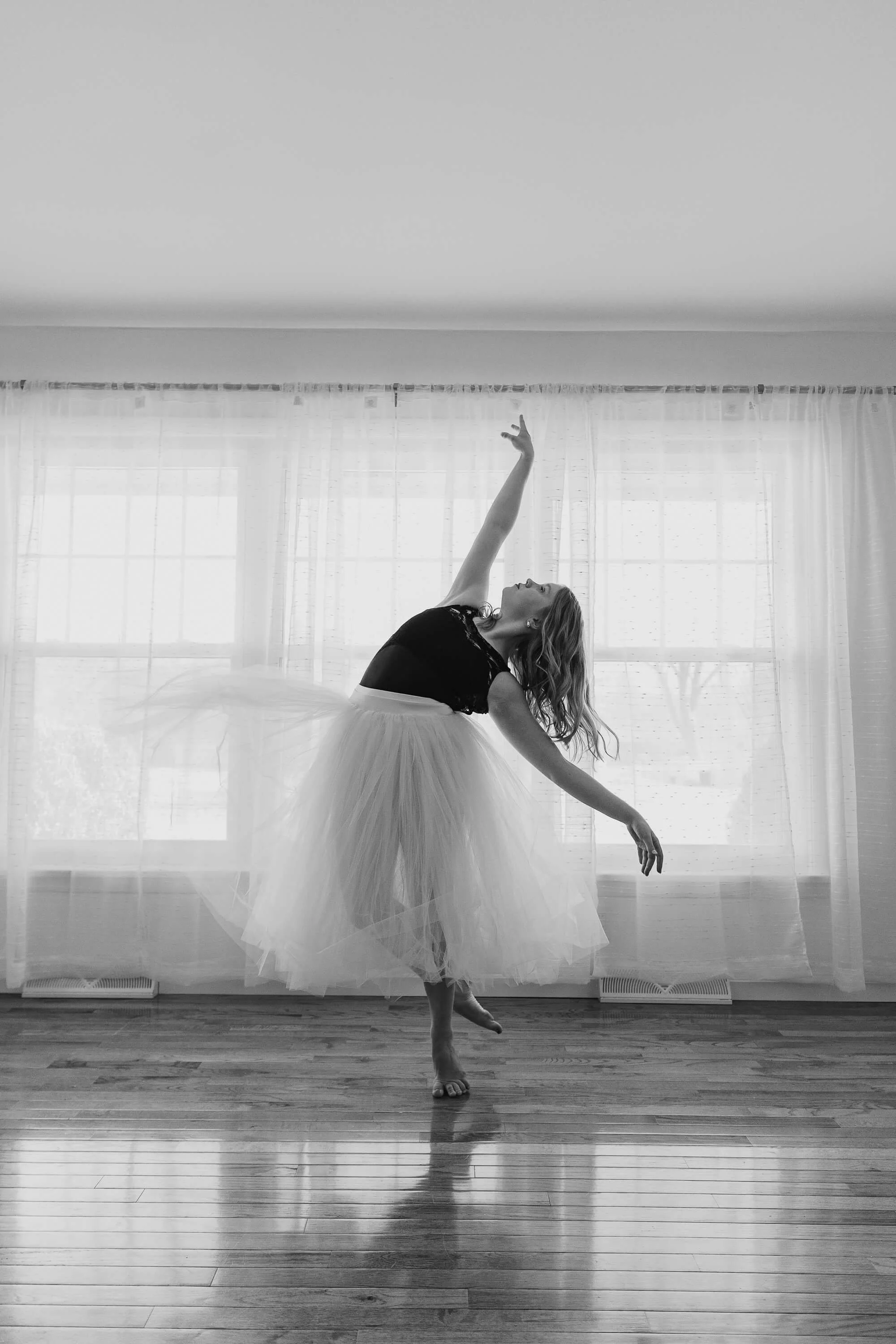 A black and white image of a ballerina wearing a romantic tutu during her studio session.