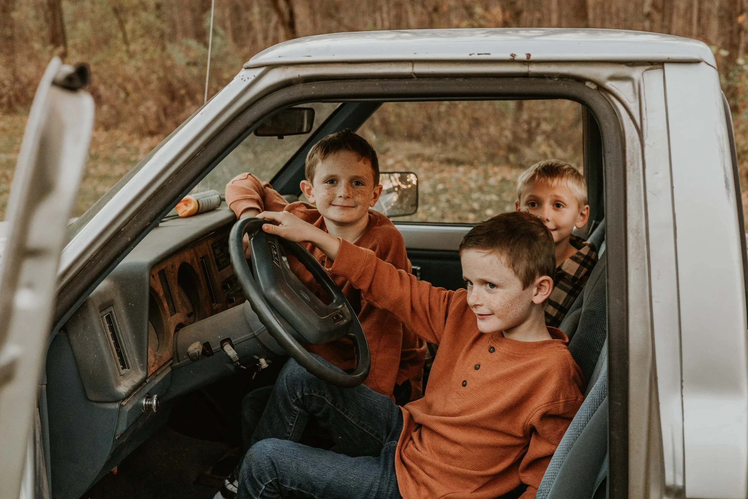 Brothers smile as they explore a beat up pick up truck