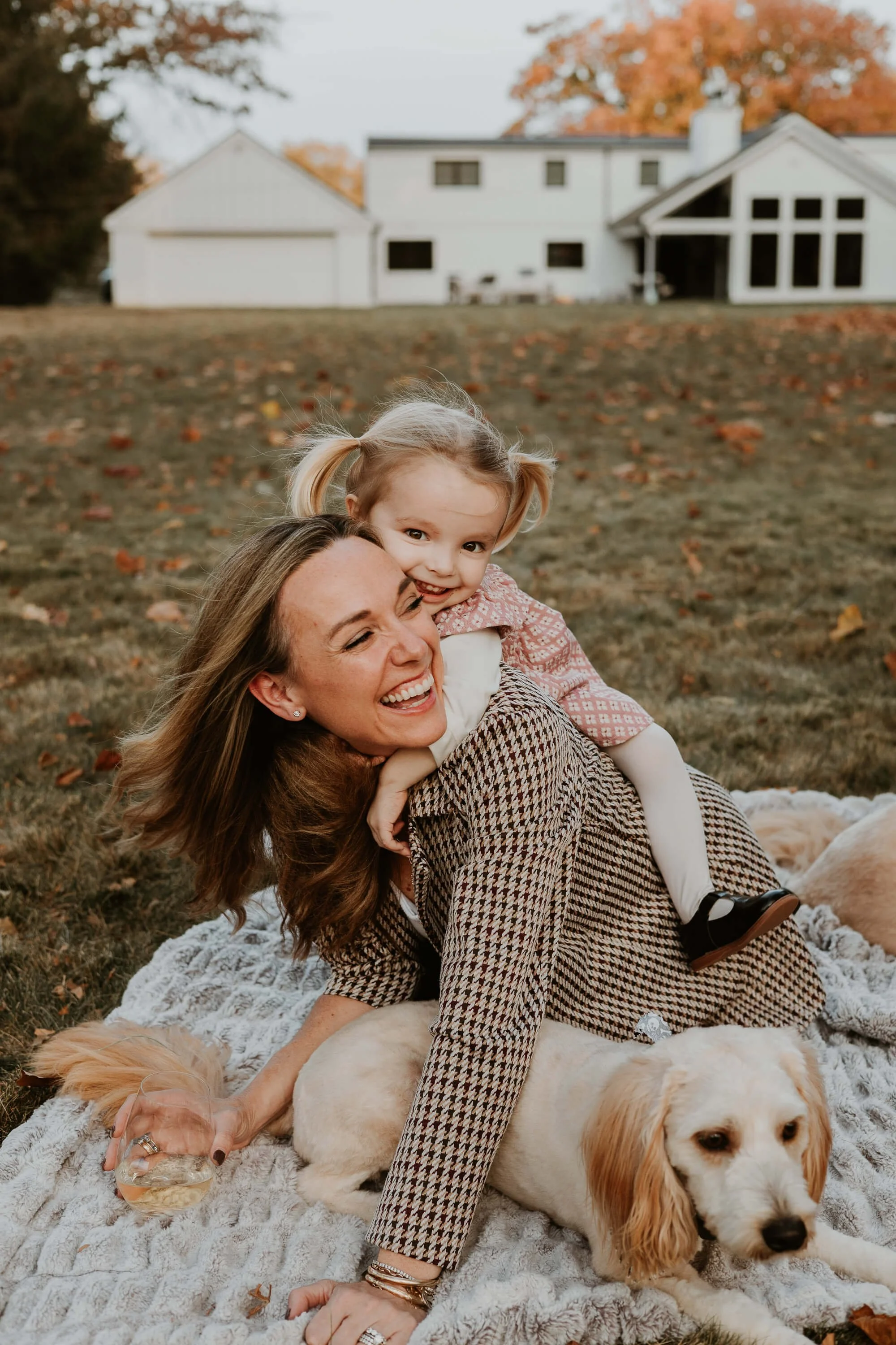 a mom sits on a blanket while her 3 year old hugs her neck