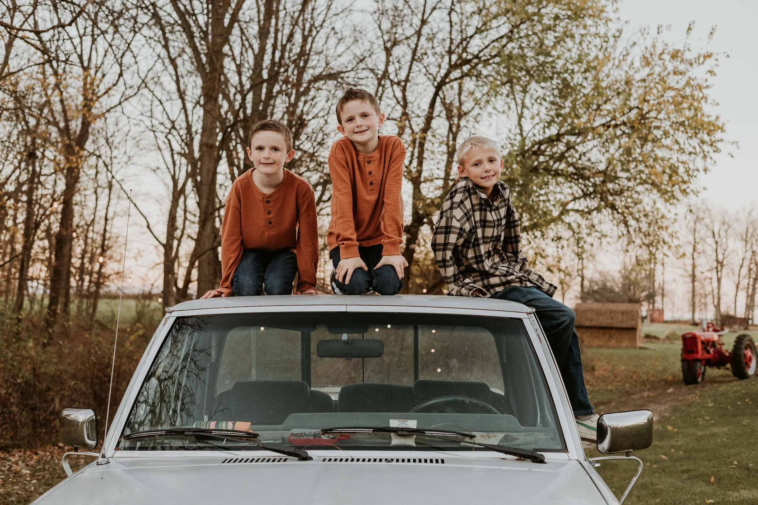 A close up of twins and their older brother as they sit atop their great-uncle's pick up truck