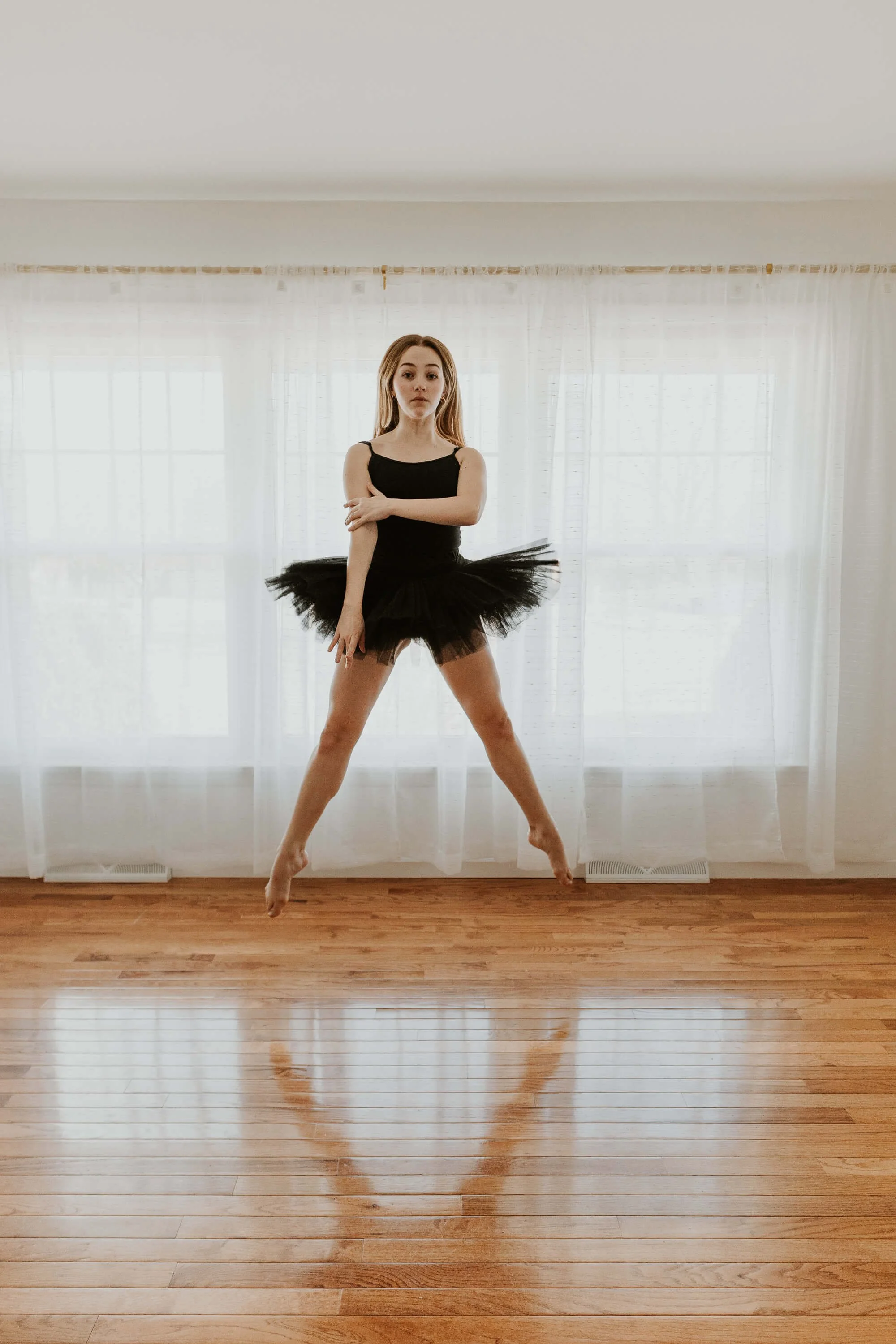 A ballet dancer shows her strength in a verticle leap in second position.
