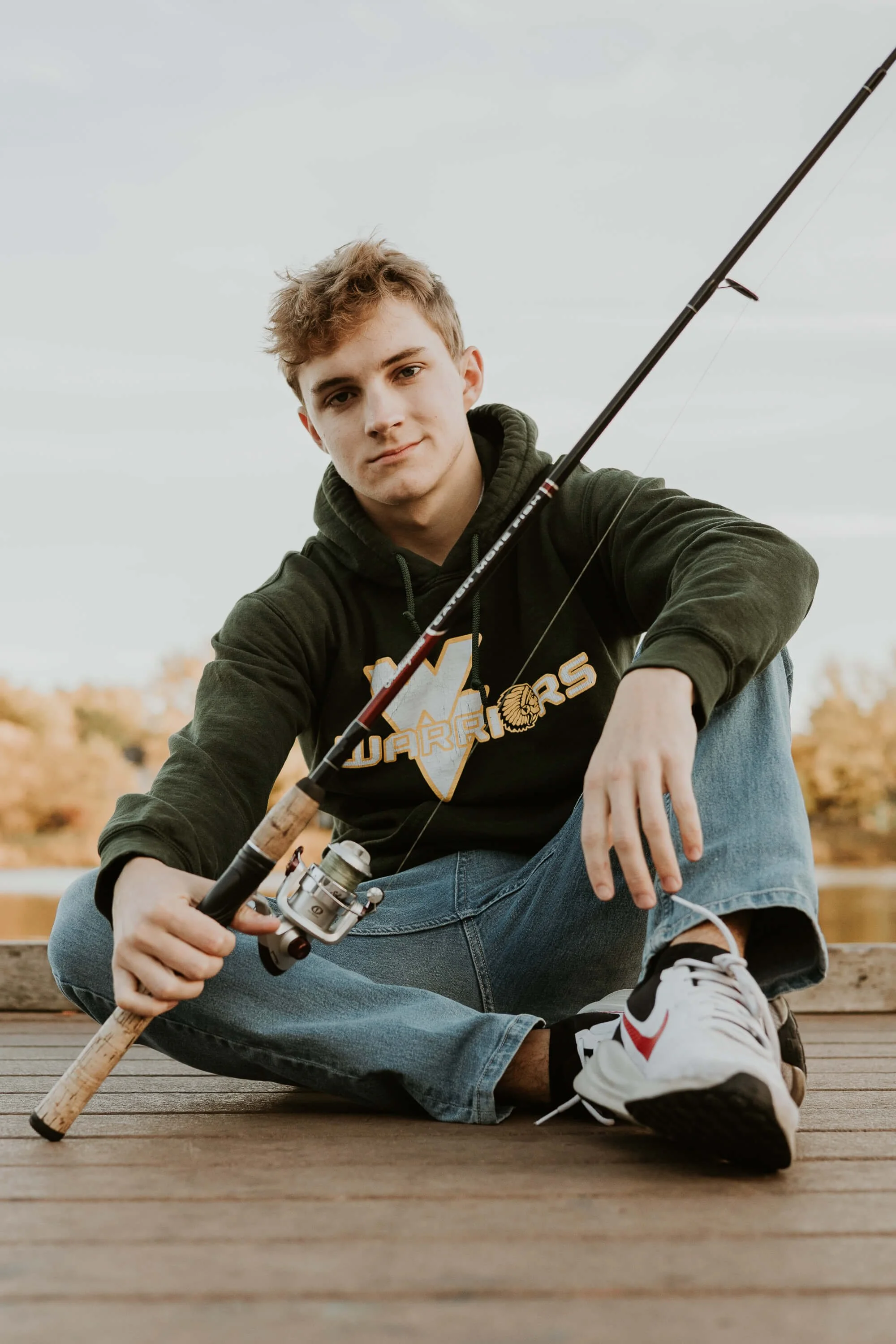 A close up of a teen boy holding his fishing gear