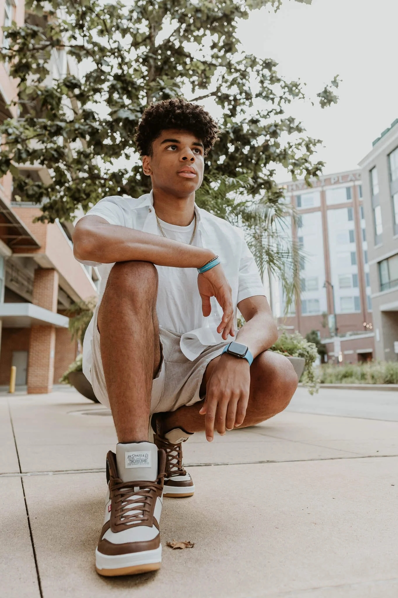 A close up of a teen boy crouched down on the sidewalk near the Normal Station.