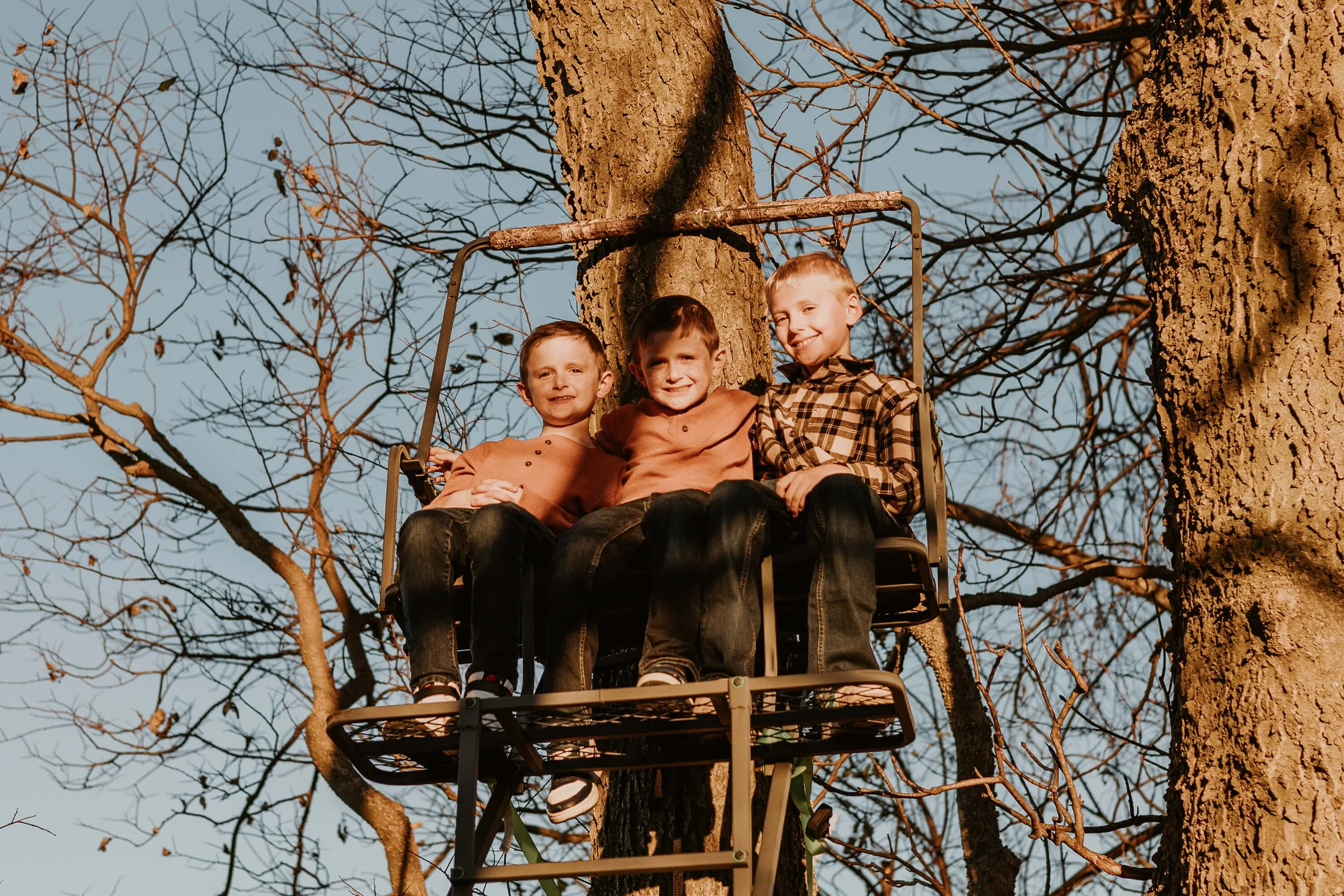 Three young brothers proudly sit atop their deer stand, overlooking their family property outside of Bloomington IL