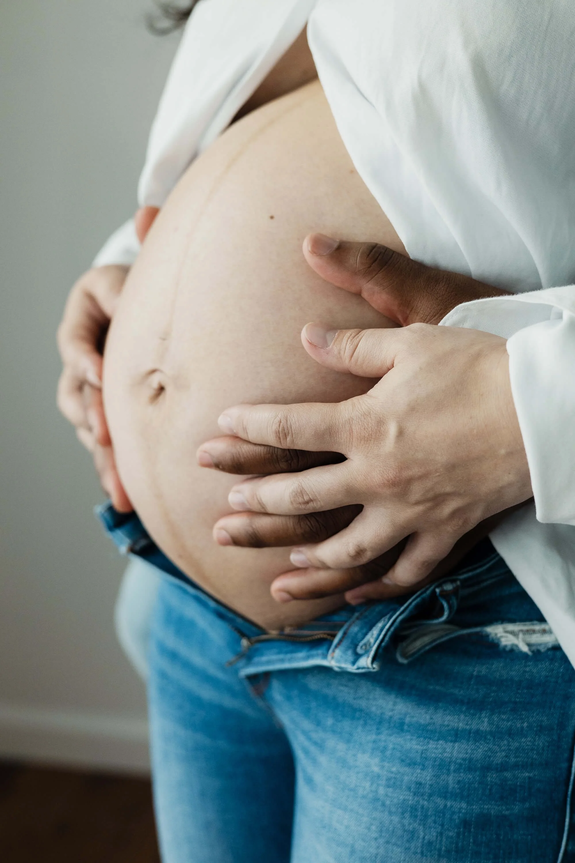 A pregnant belly is held by both mom and dad's hands