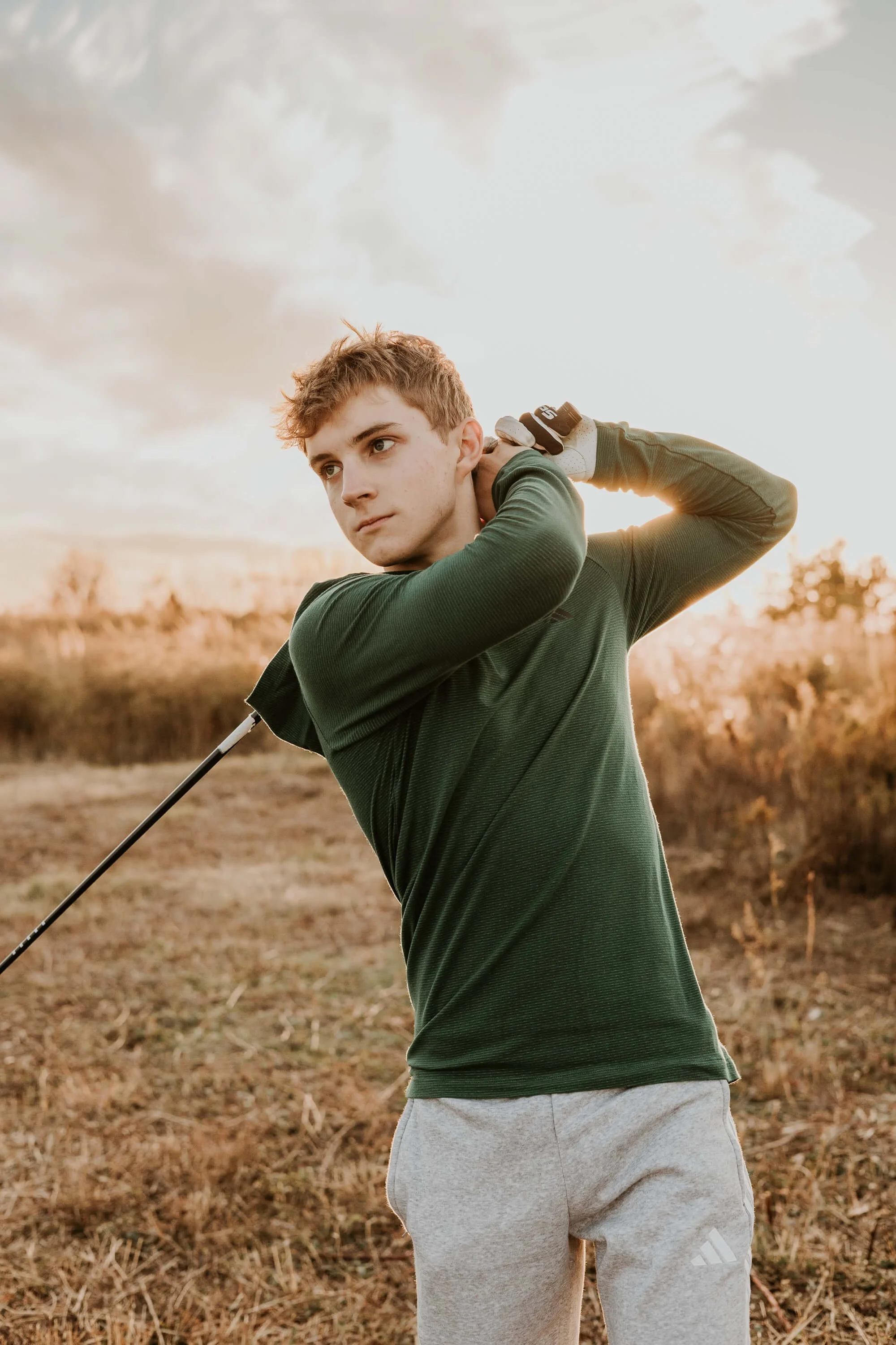 A teen boy holds a golf swing