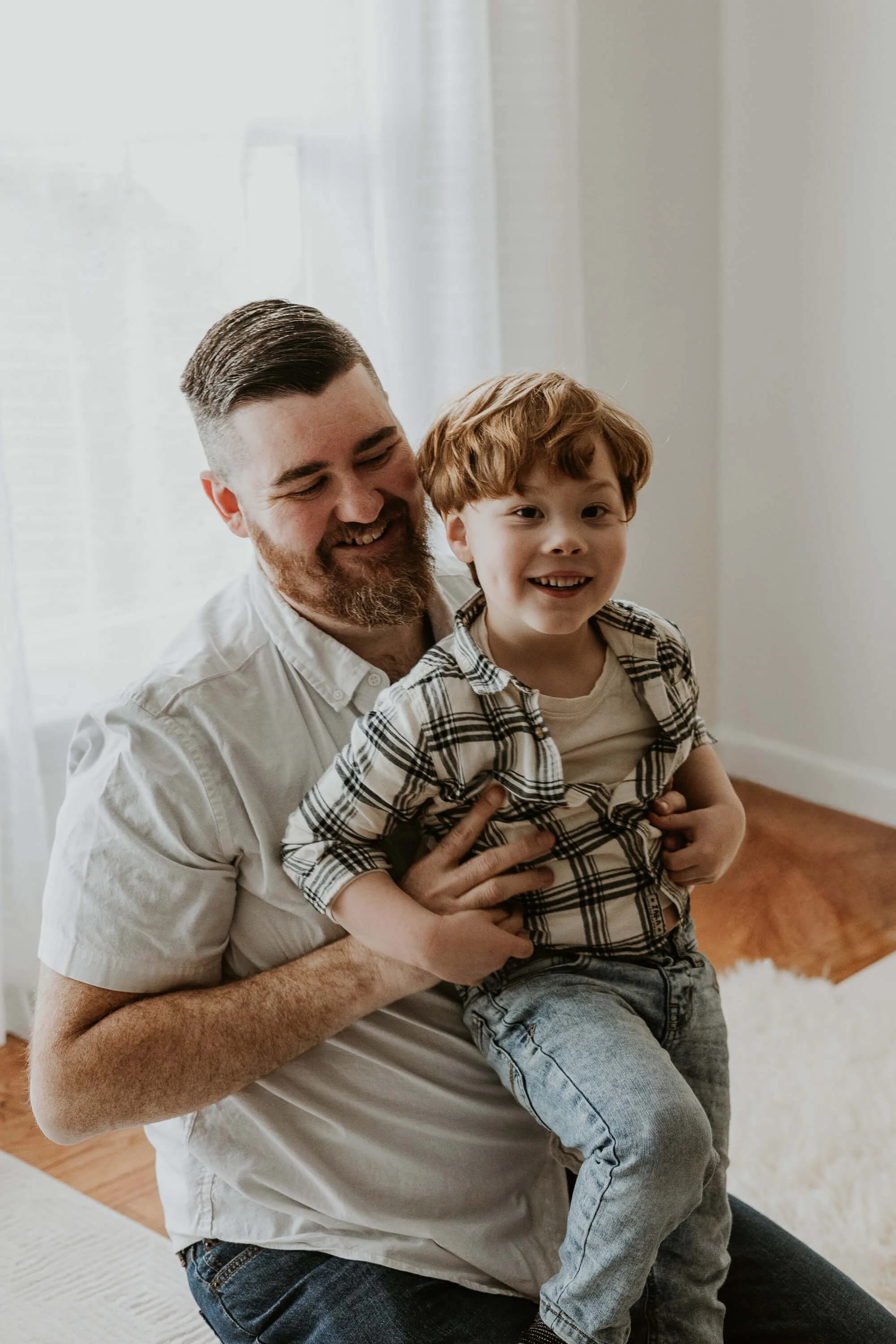 A father tickles his son's belly as they both smile and laugh
