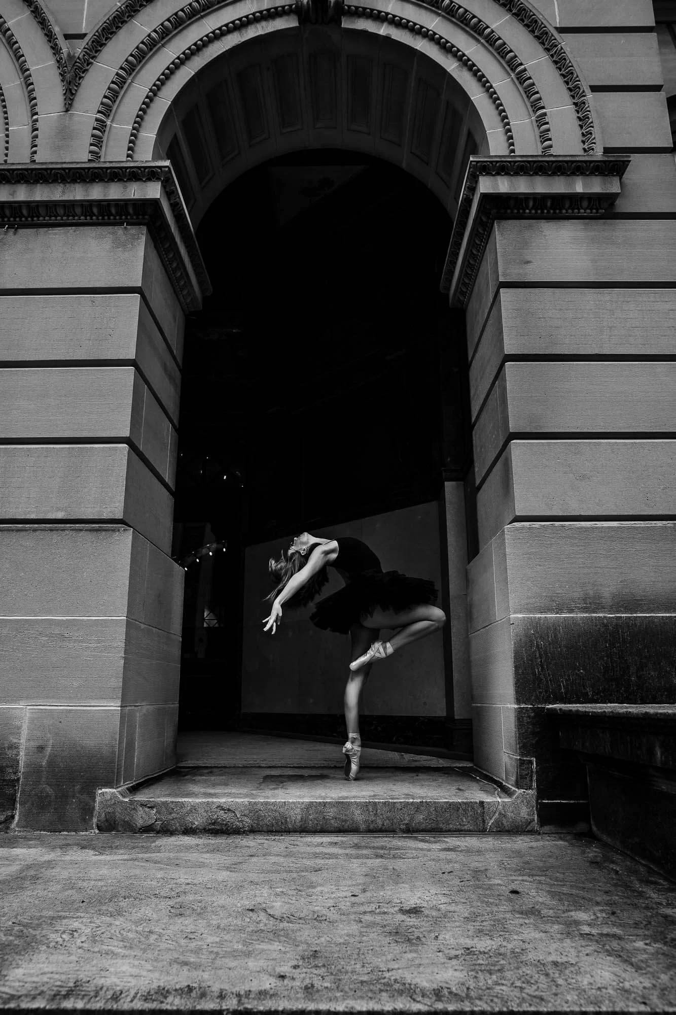 A talented dancer strikes a pose en pointe in front of an archway at the McLean County Museum in Bloomington IL