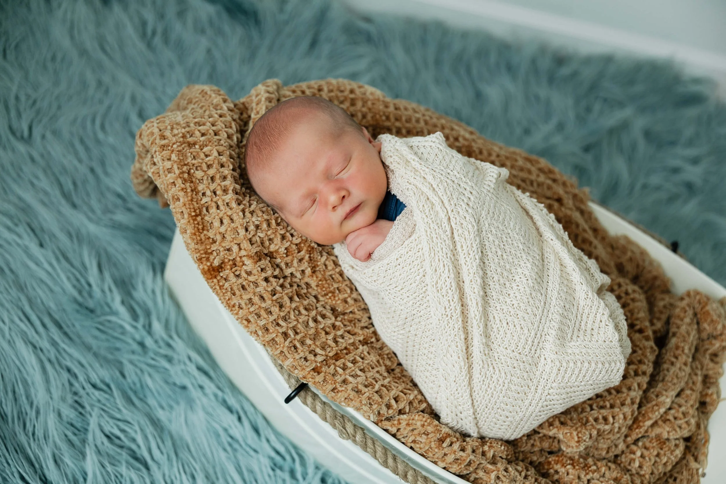 Nestled in a baby-sized boat stuffed with plush blankets, a newborn sleeps peacefully