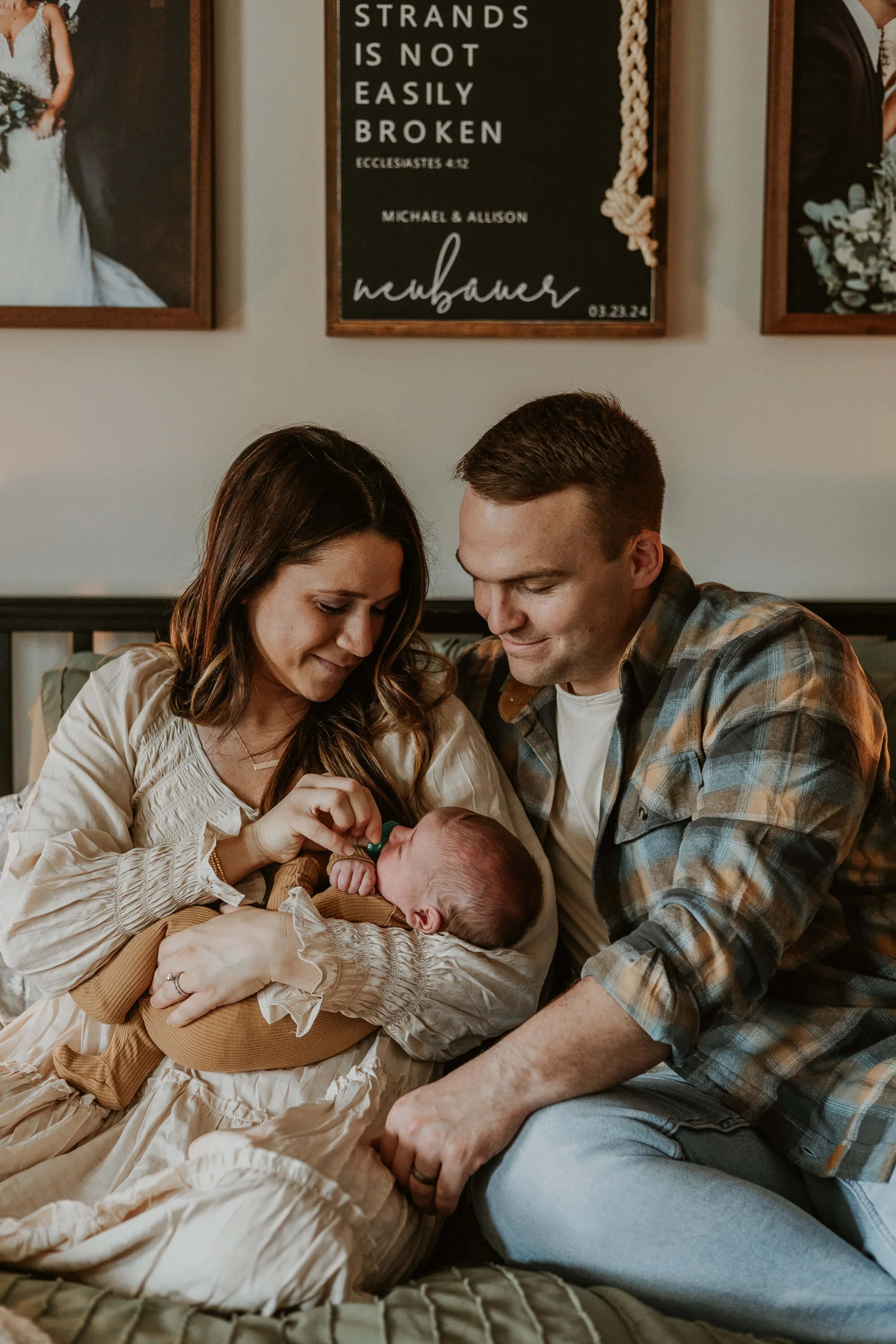 New parents smile down at their son while sitting peacefully in bed together