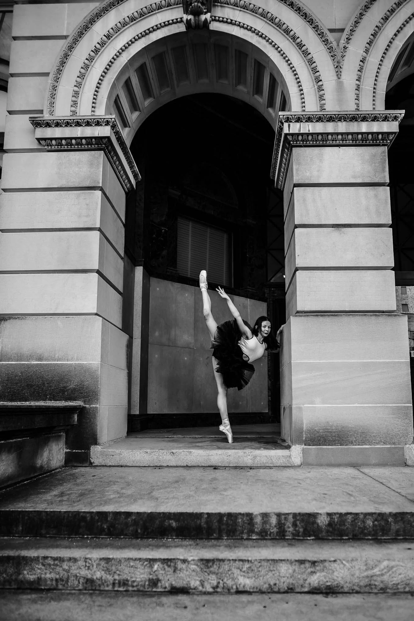 A black and white image of a dancer striking a pose outside the McLean County History Museum.