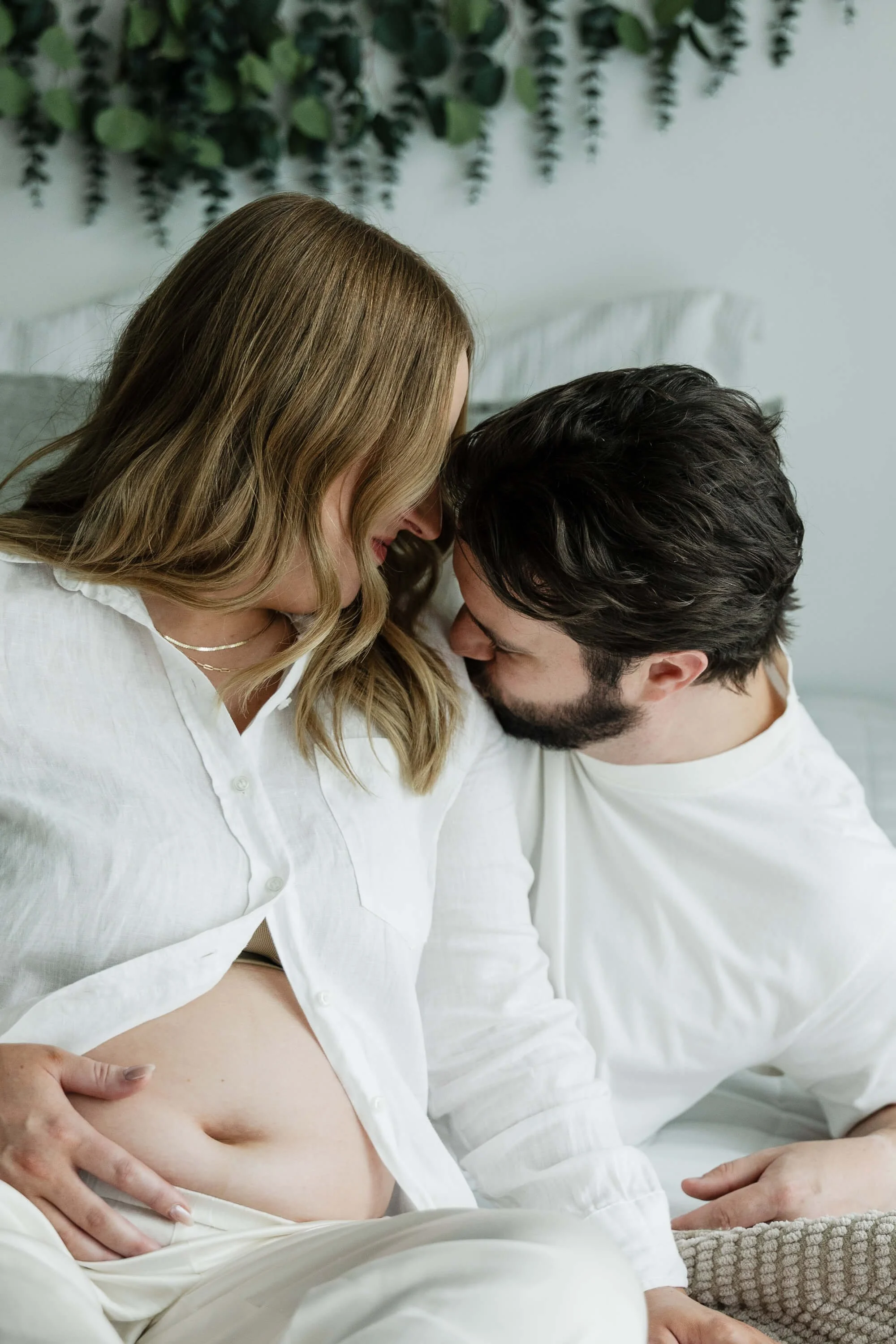 A mom and dad-to-be are nose-to-nose during a quiet moment in Liz Walsh Photography's studio