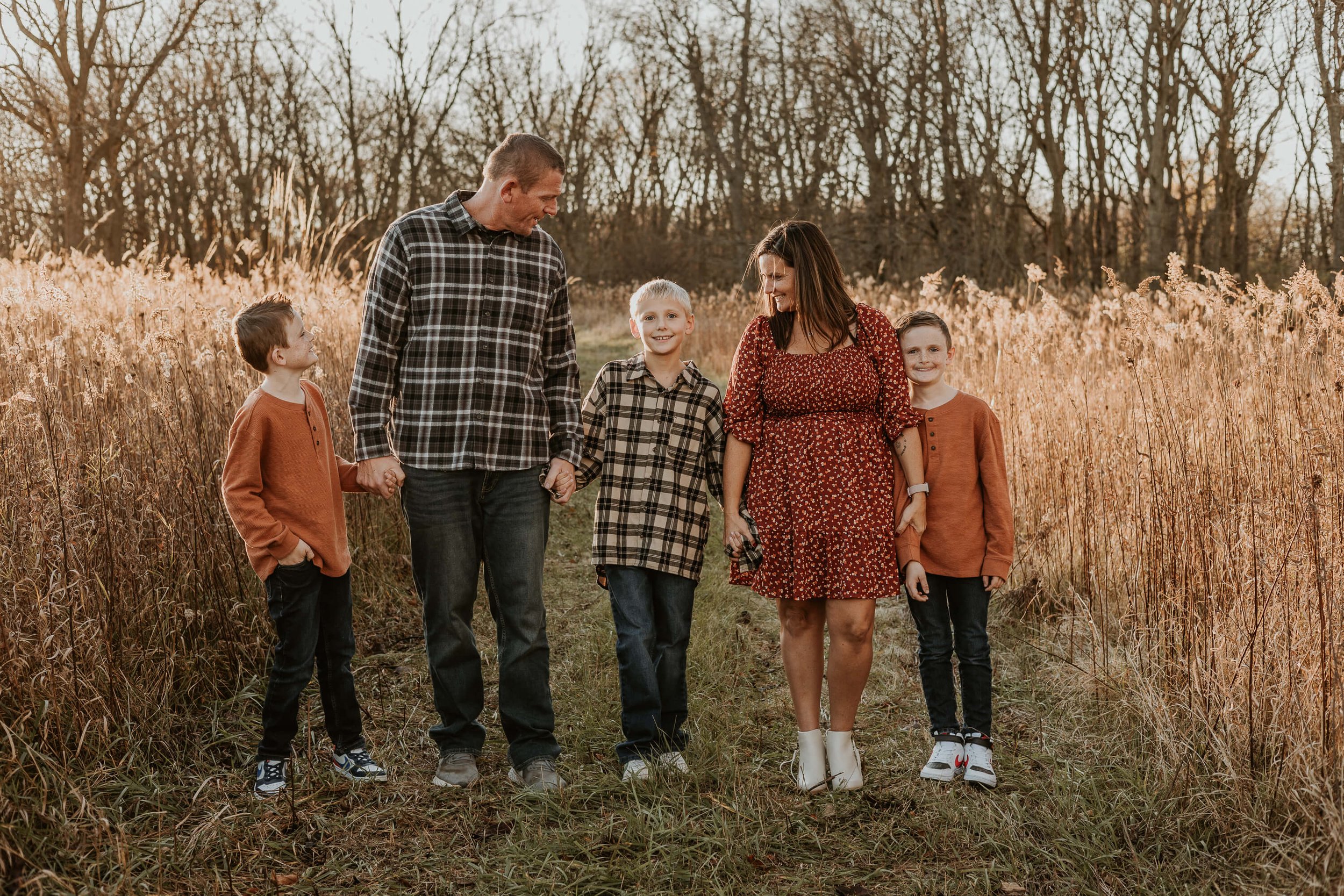 A family of five stand on a mowed path, surrounded by tall prairie grass on their family farm