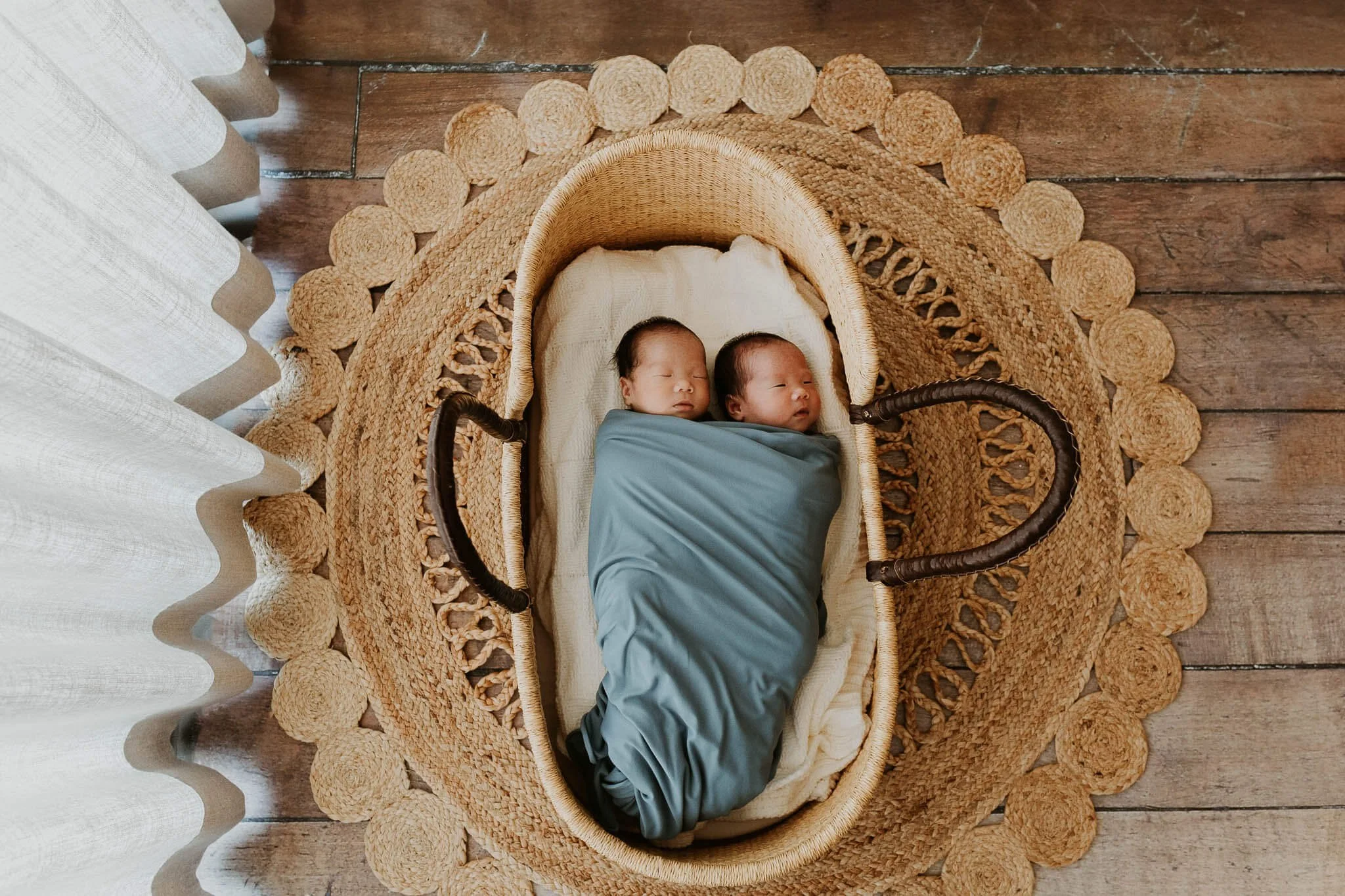 Identical twin brothers are swaddled in a moses basket