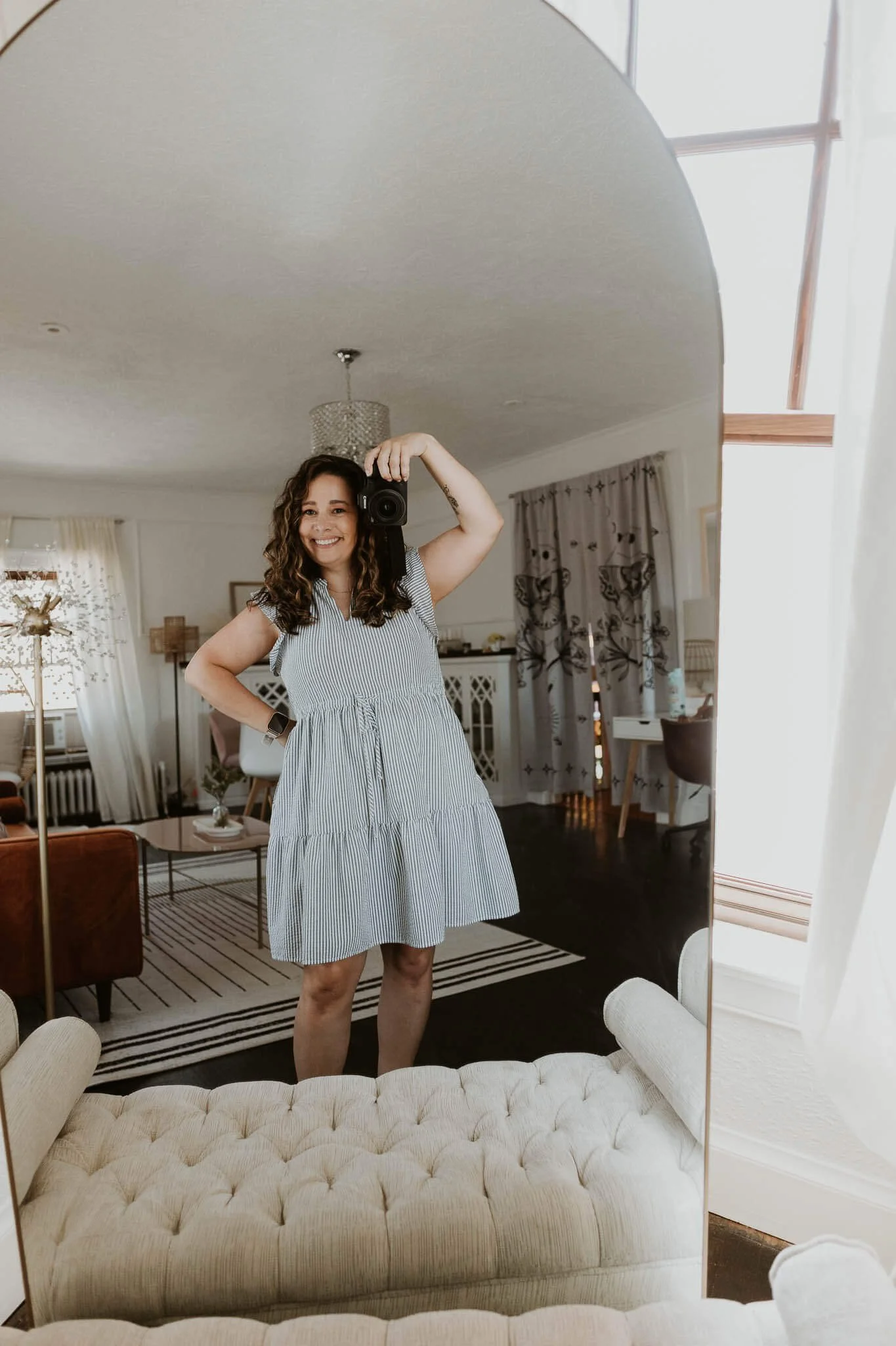 Liz Walsh stands facing a mirror smiling while holding her Canon camera up in a pose
