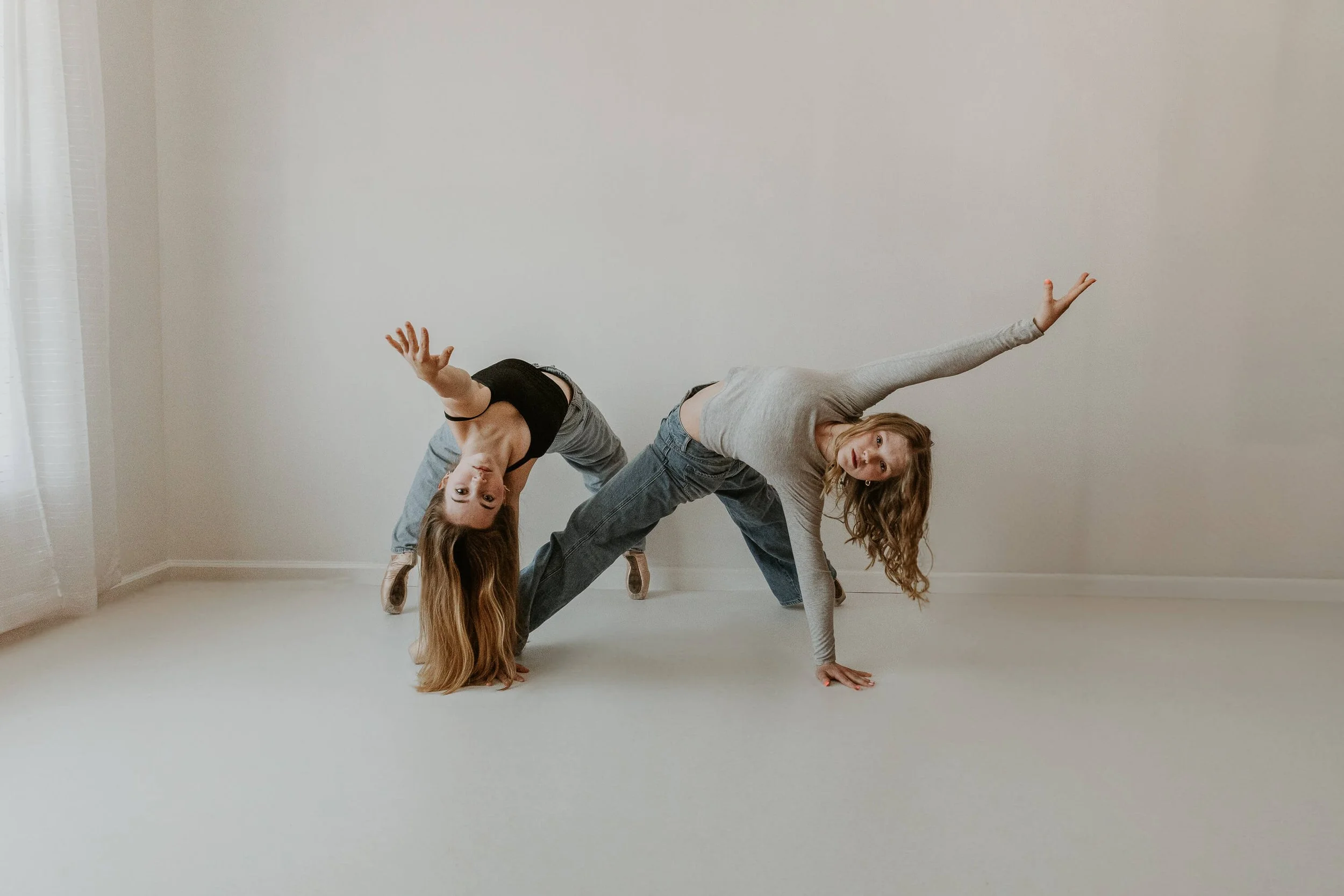 Two high school dancers hold a backwards bridge pose in tandem.