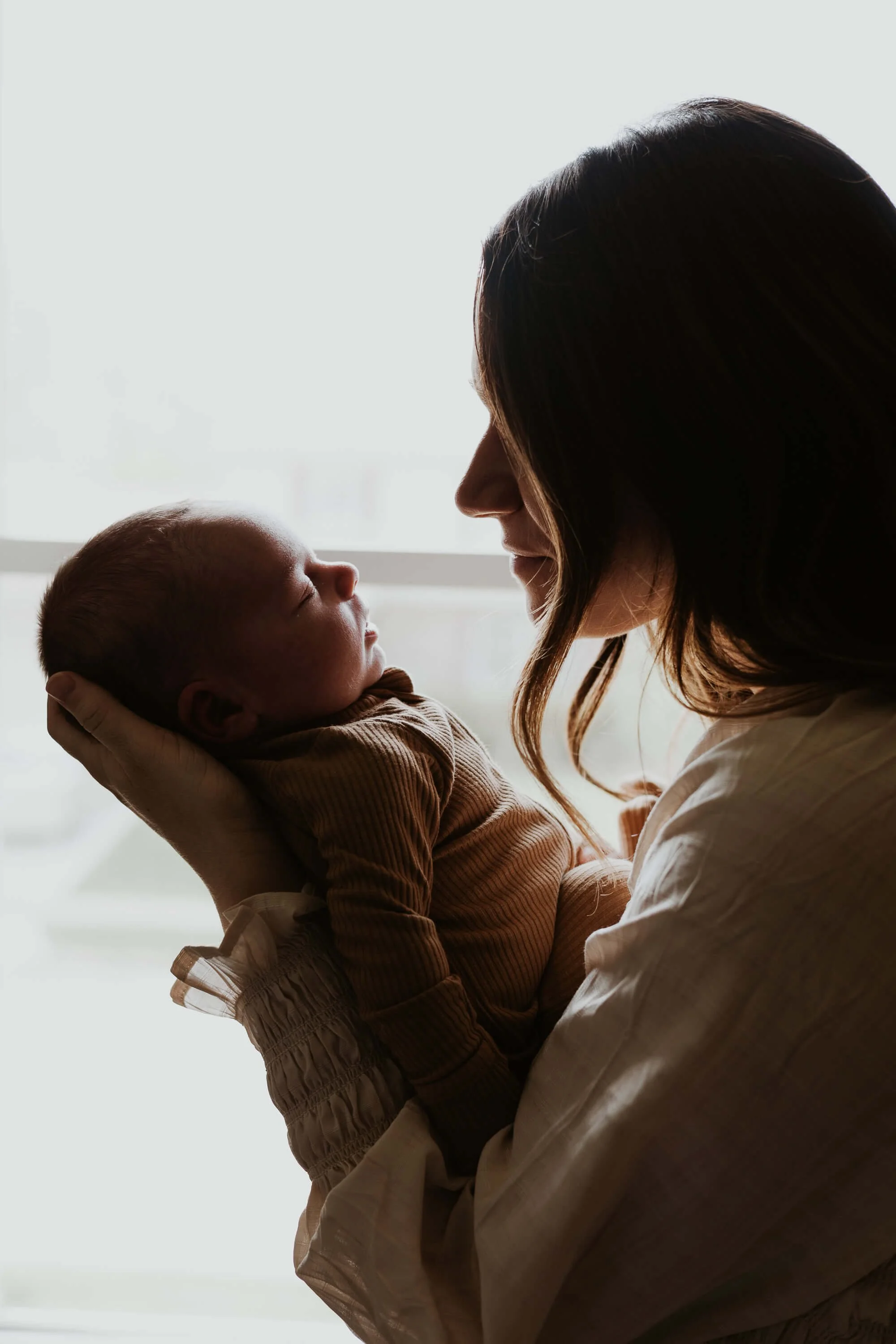 A mother admires her newborn son while he sleeps
