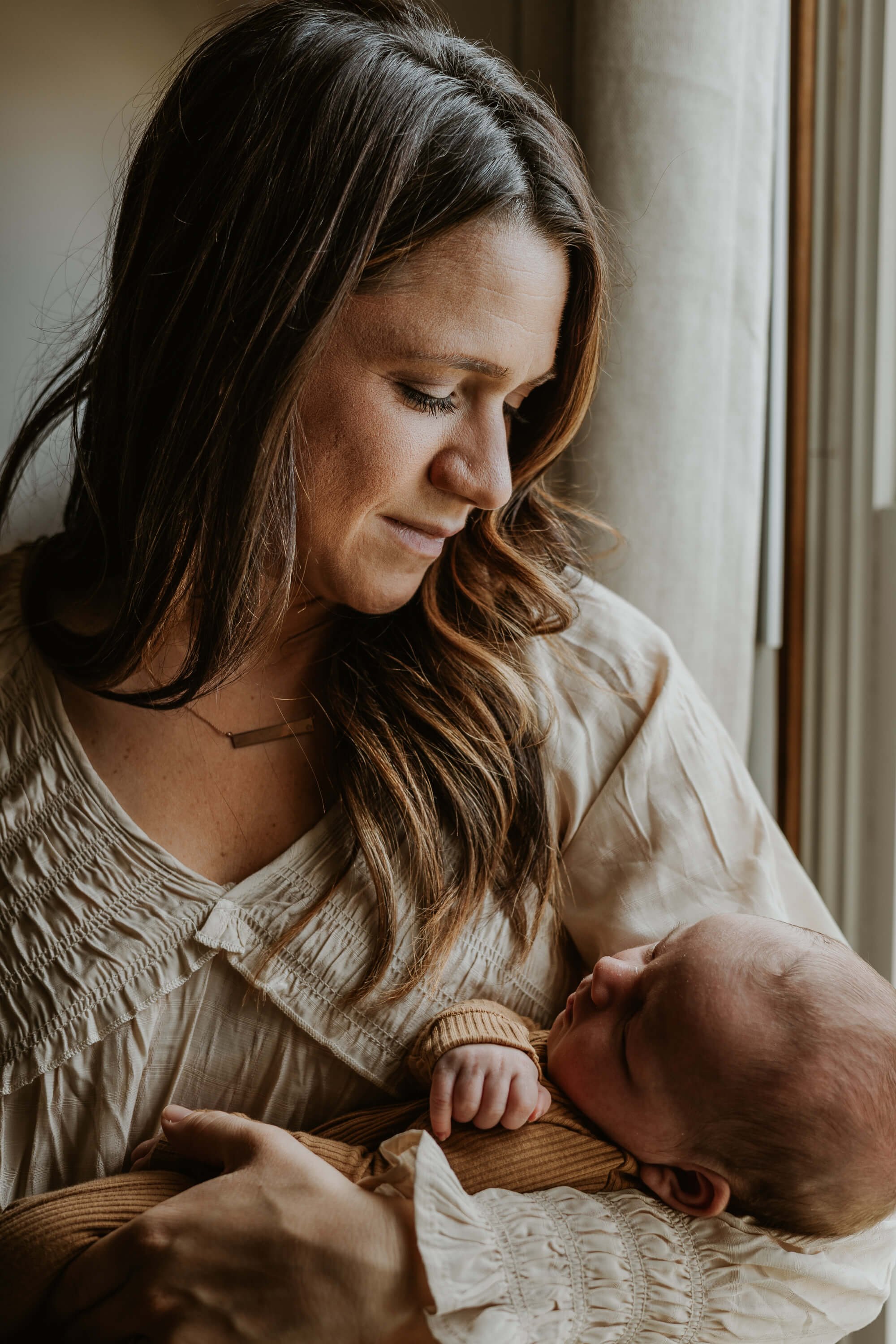 A mother holds her newborn gently in the crook of her arm