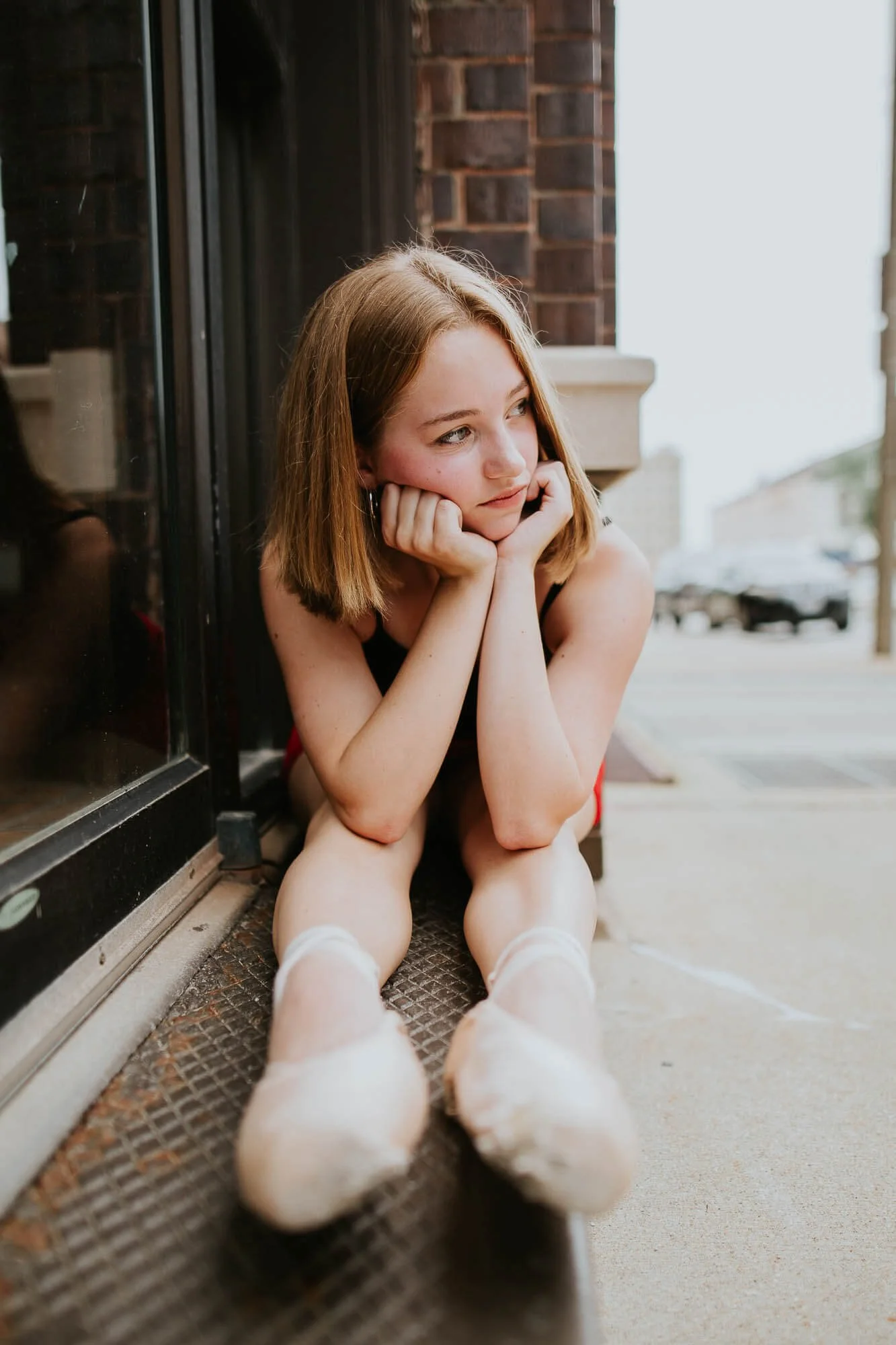 A ballerina holds a stretch at the doorway of a local business