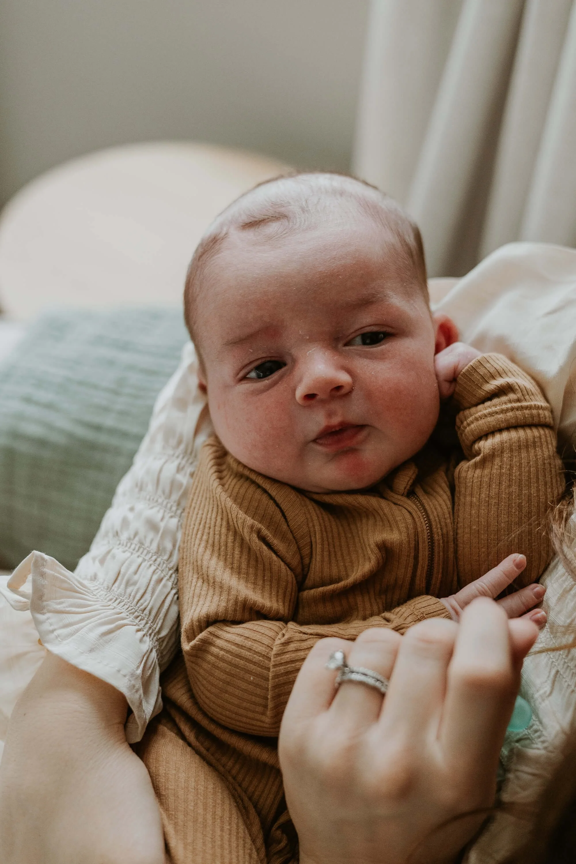 A wide-awake baby stares curiously up at his mother