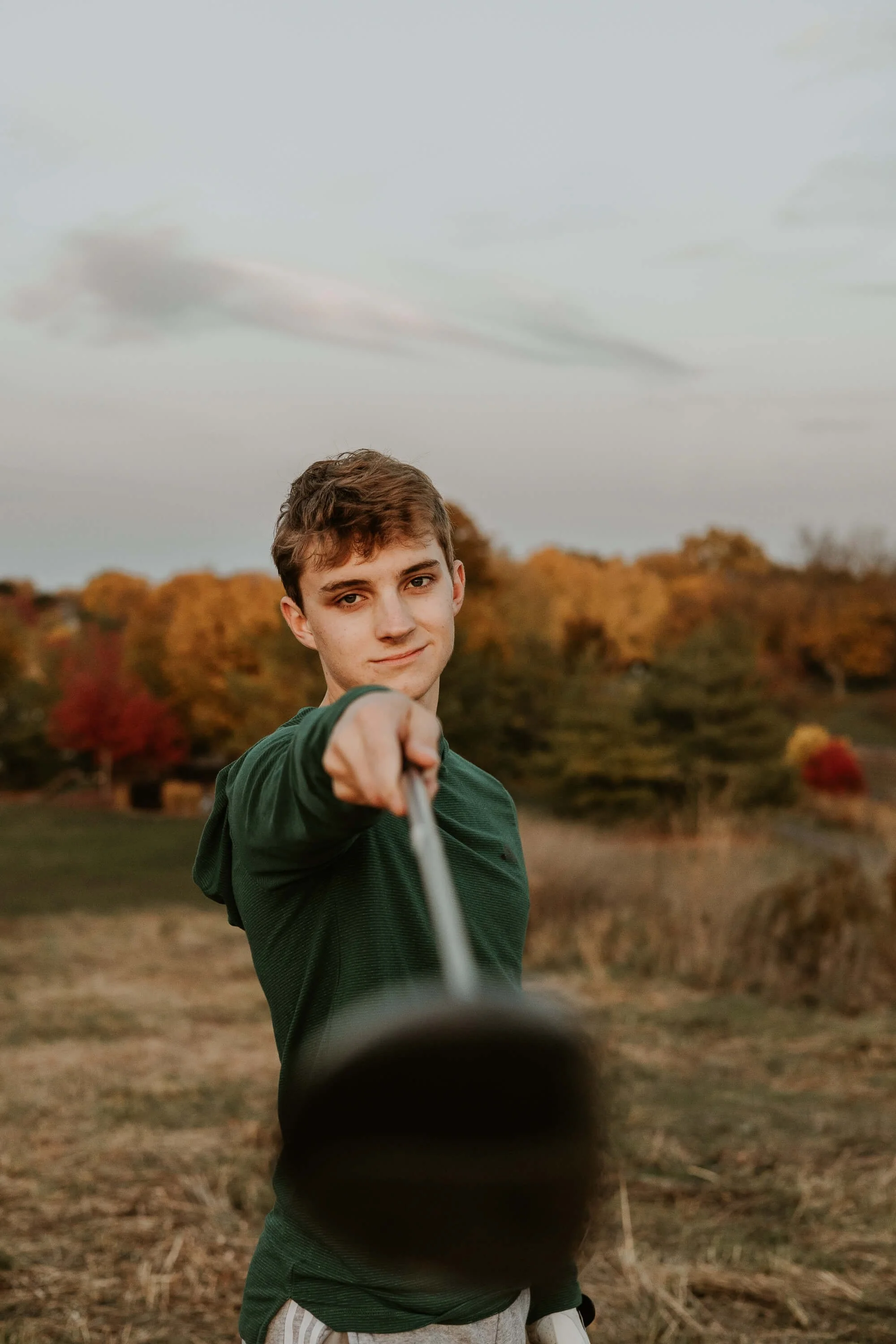 A high school senior holds his golf club out directly in front of him, a small smile on his face.