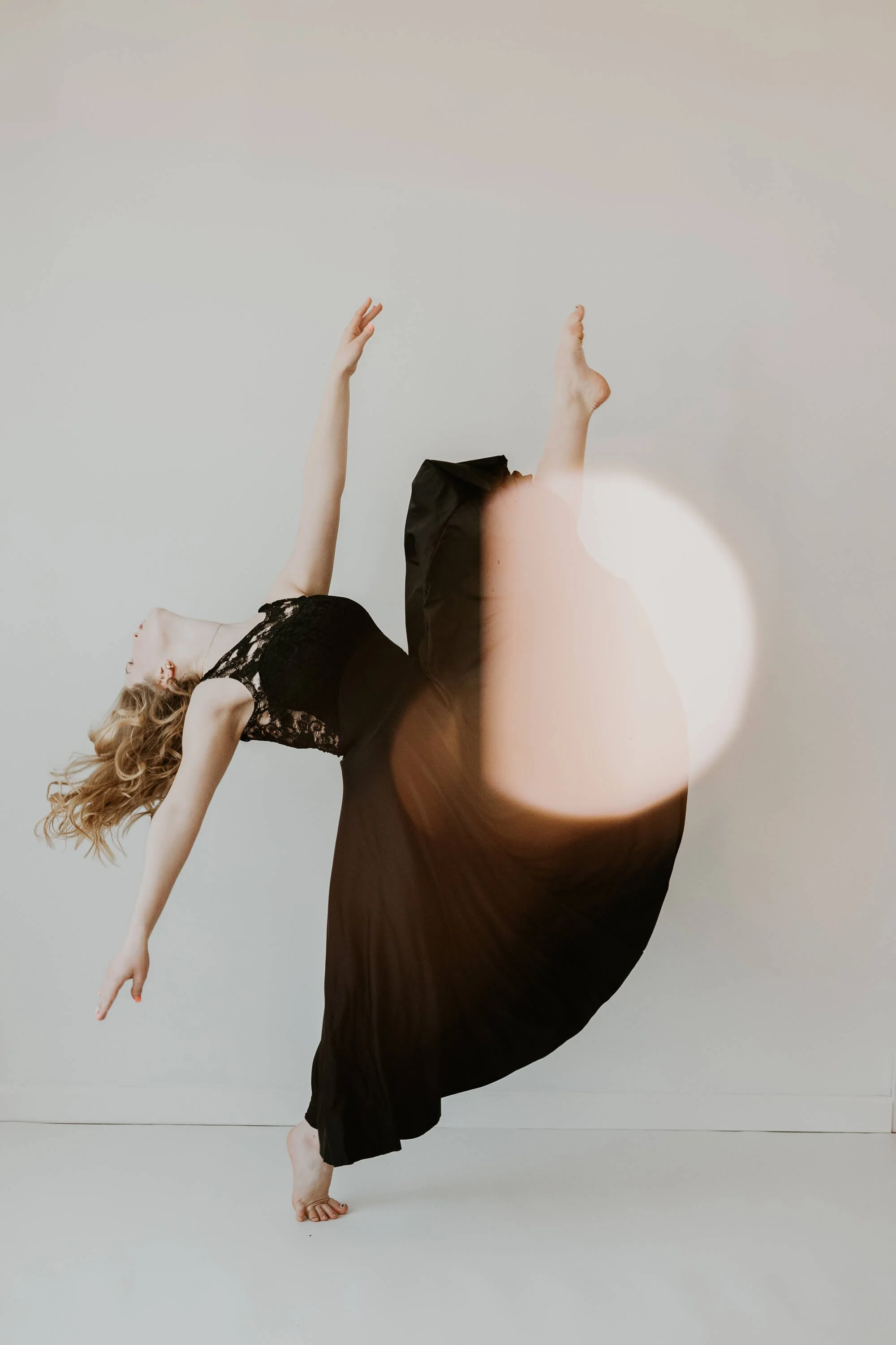 A dancer on one foot, with the other flung directly up, arches her head backwards in a seemingly effortless pose.