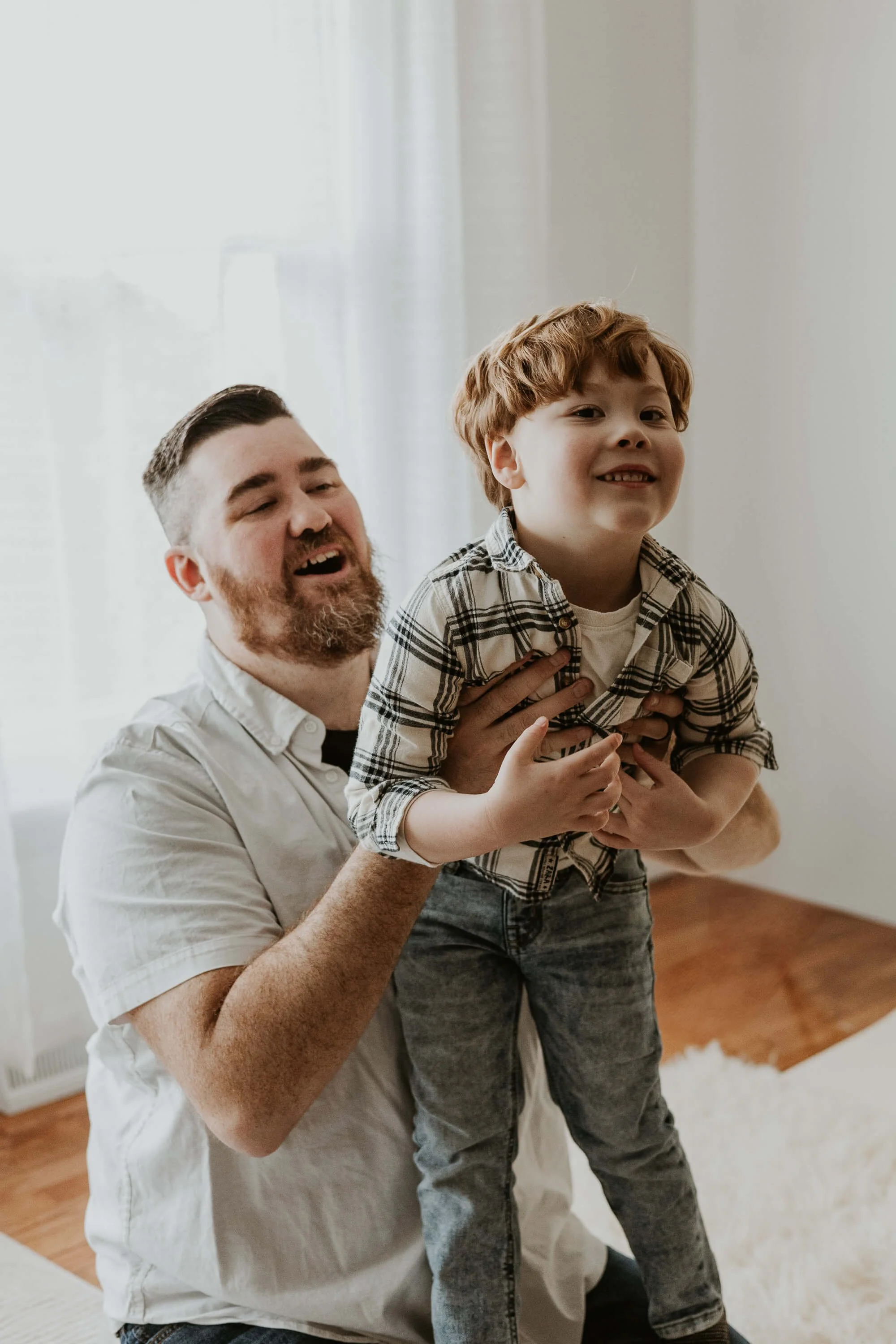 A father and son playfully tickle one another