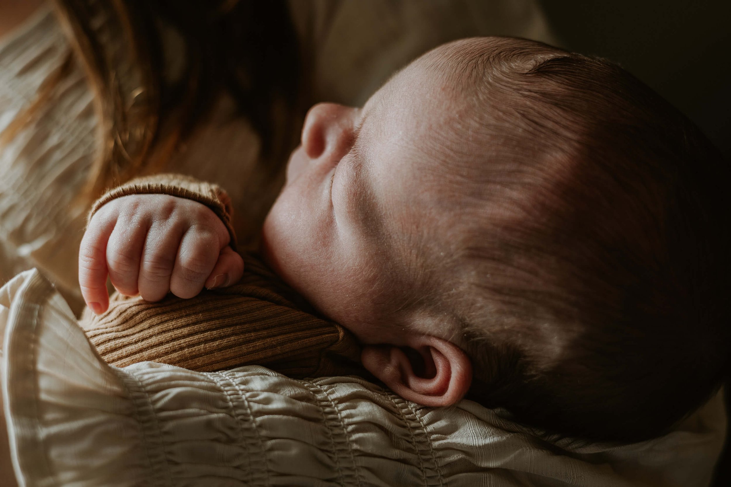 A close up profile of a newborn baby boy sleeping peacefully