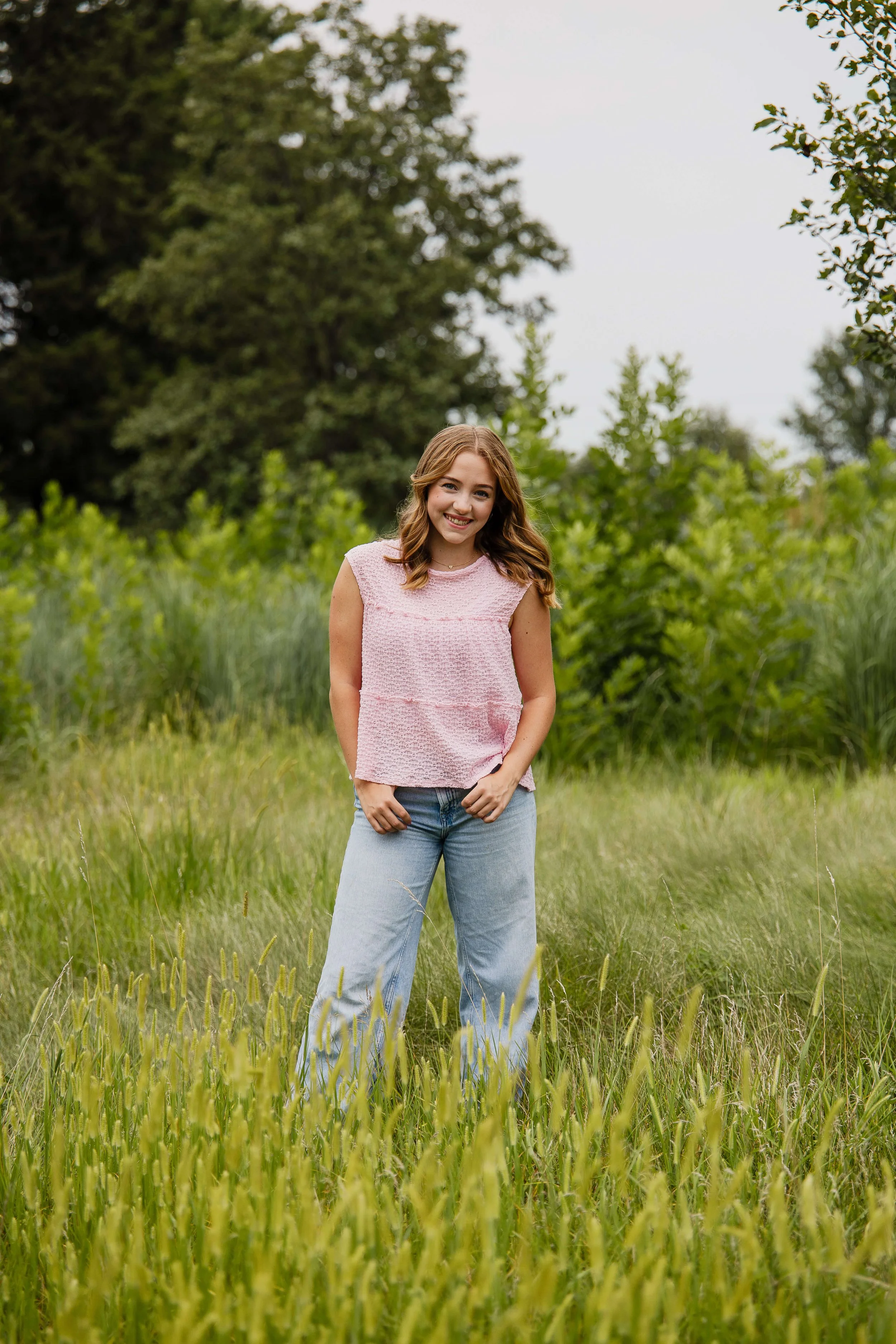 A high school senior at NCHS wears classic boyfriend jeans and a cute A-line, sleeveless pink top.