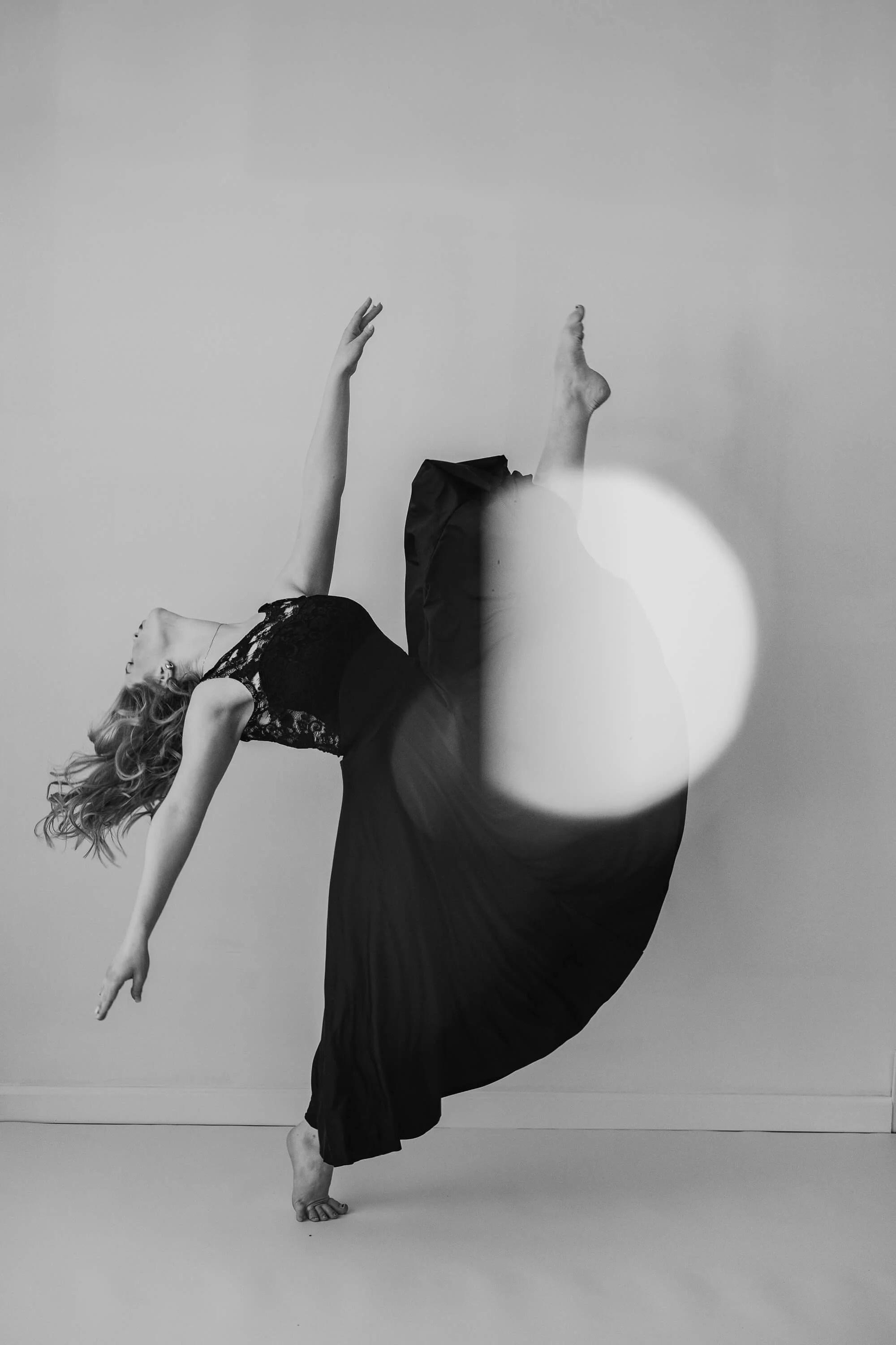 A black and white of a dancer in all black, looks like she's floating.