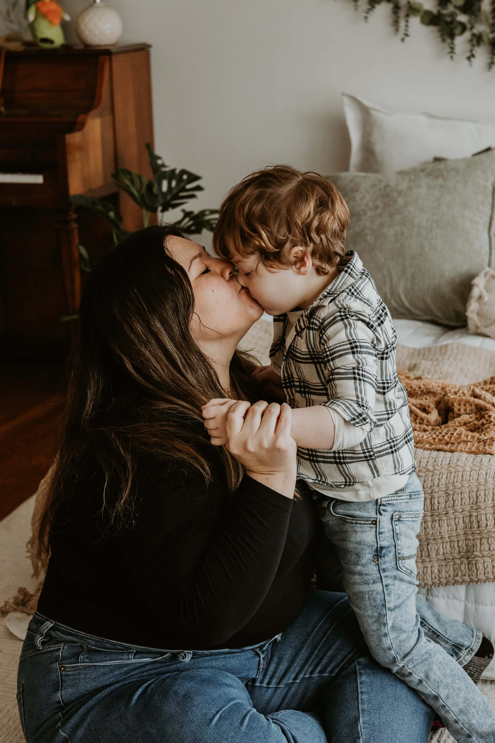 A four year old boy plants a kiss on his mother's lips