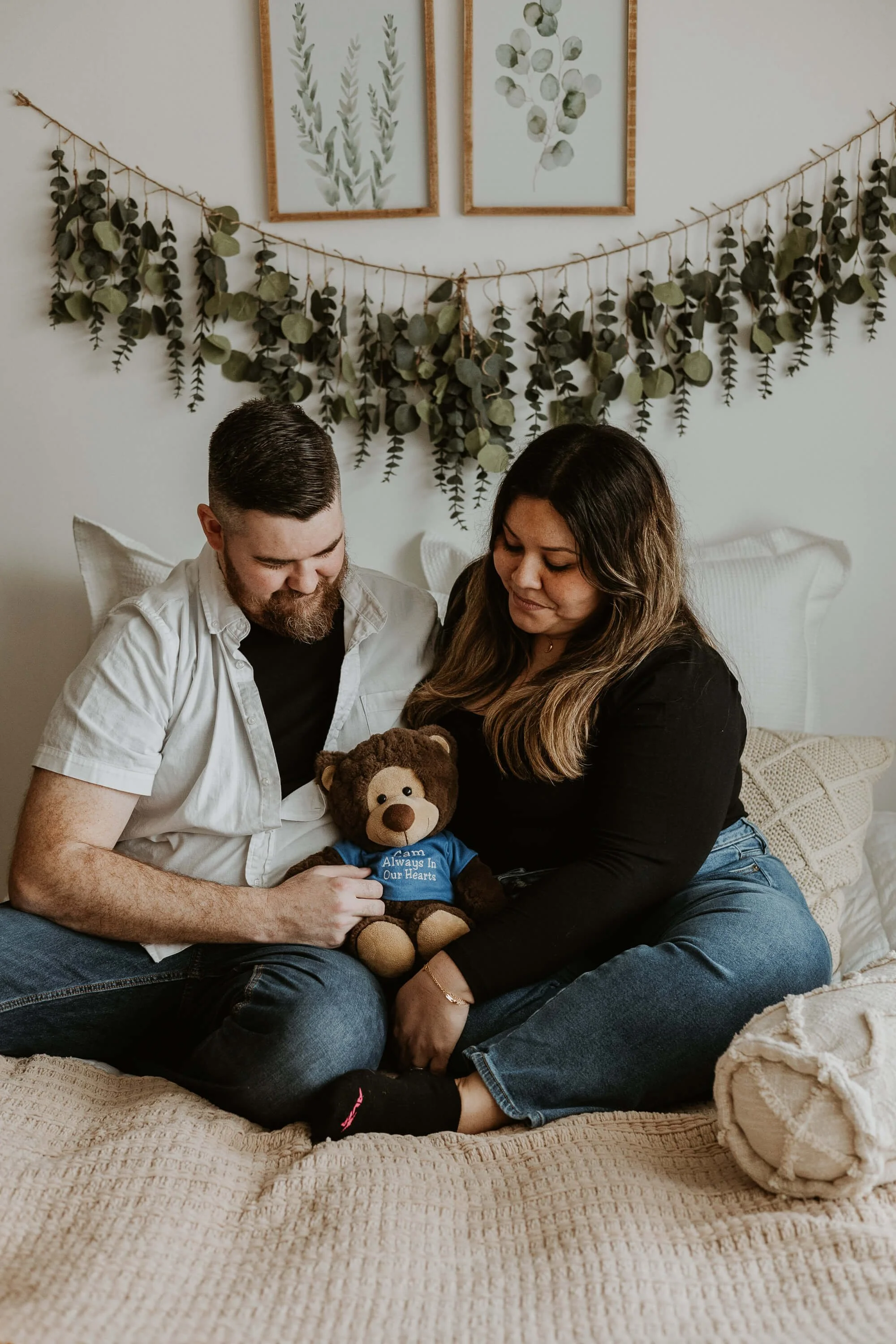 A couple look down at a teddy bear that is in memory of their first born child