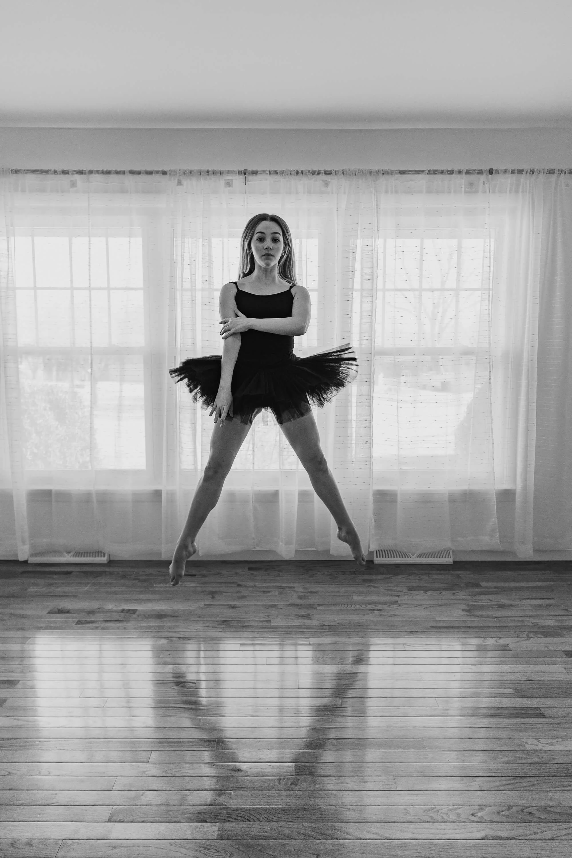 A black and white image of a dancer in second position, jumping vertically.