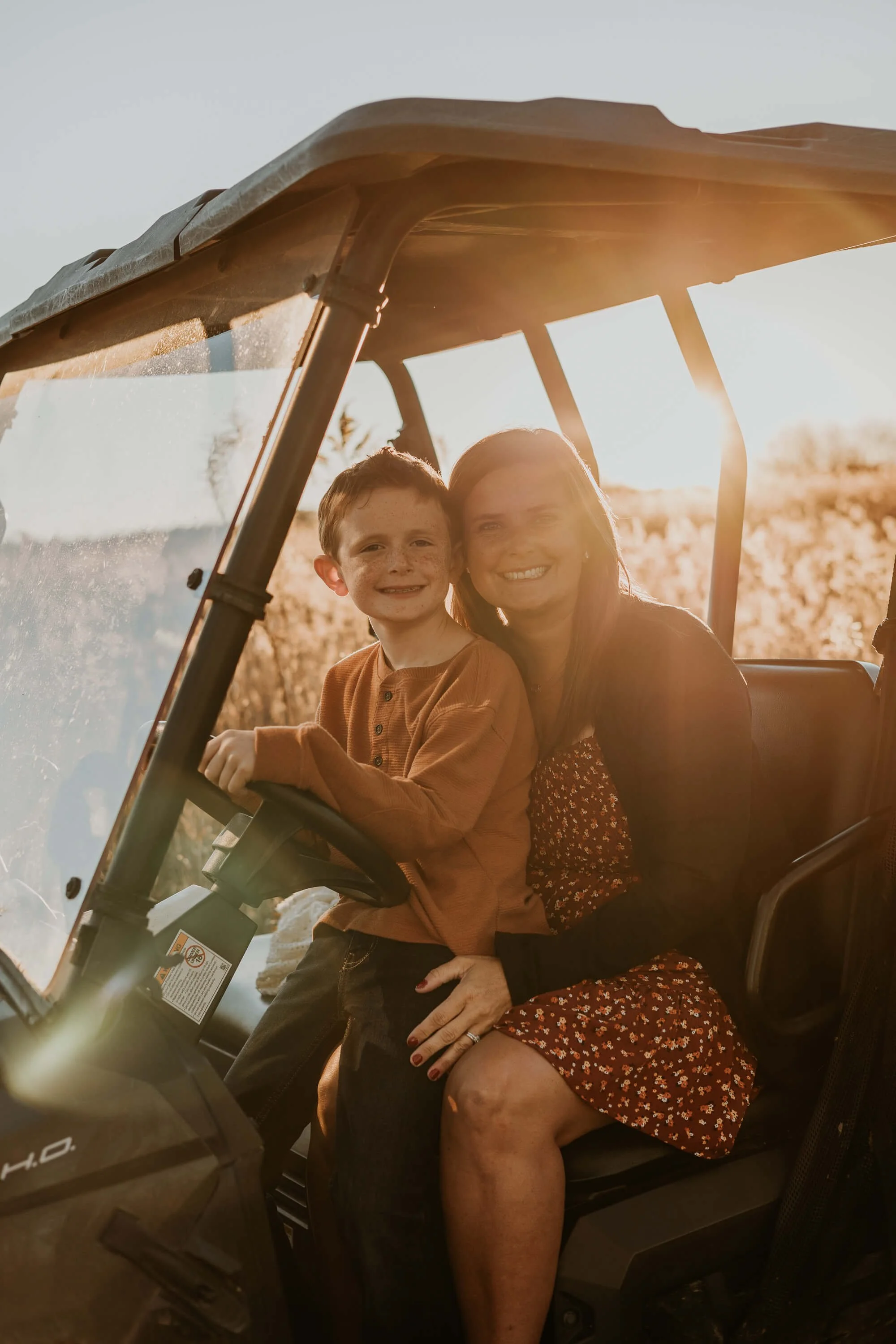 A mother snuggles her youngest son as the sun sets behind them