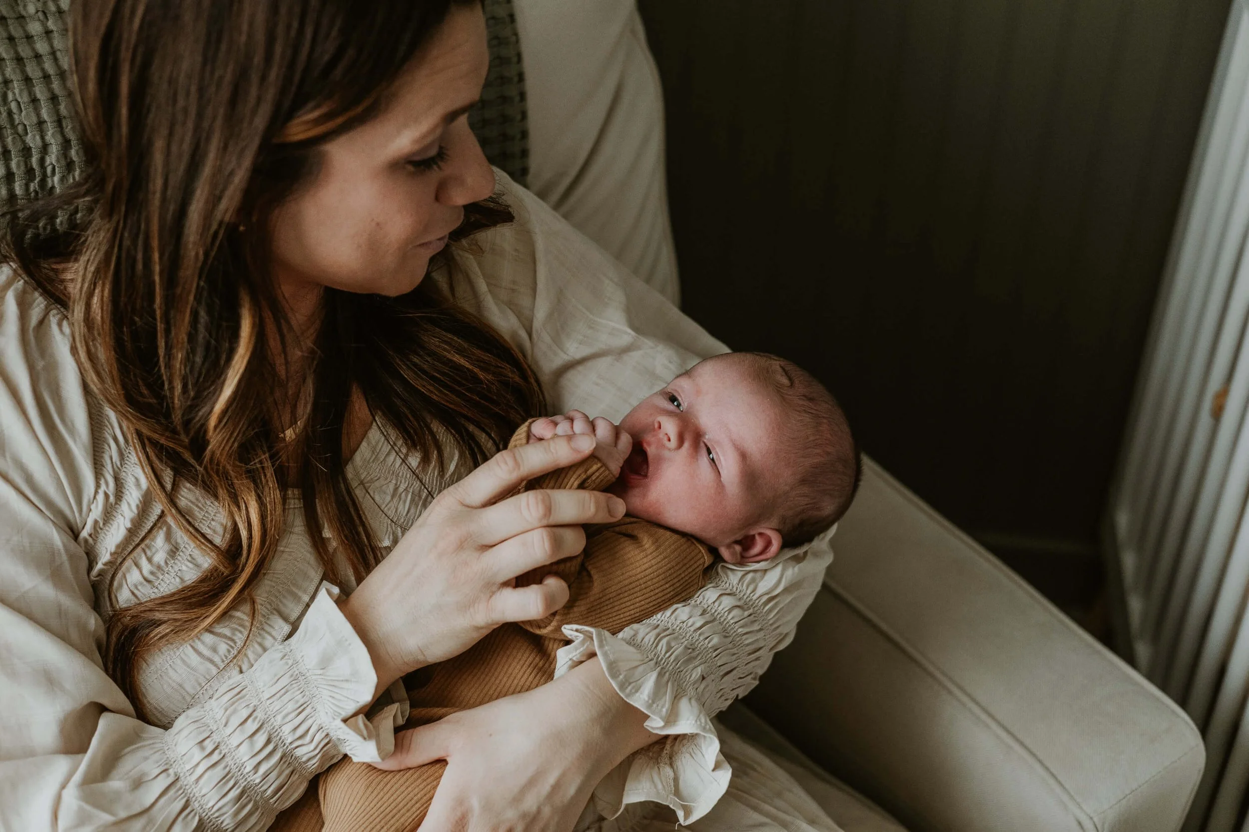 A newborn snuggles peacefully in the crook of his mother's arm