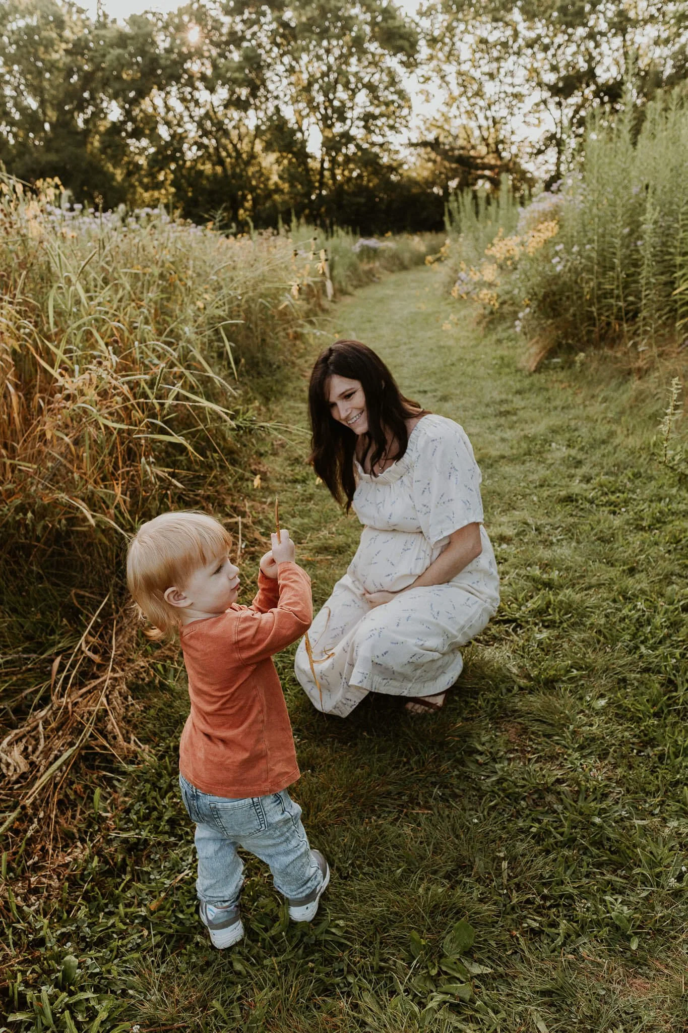 A mother and son explore the prairie flowers on the edge of a mowed path at a park